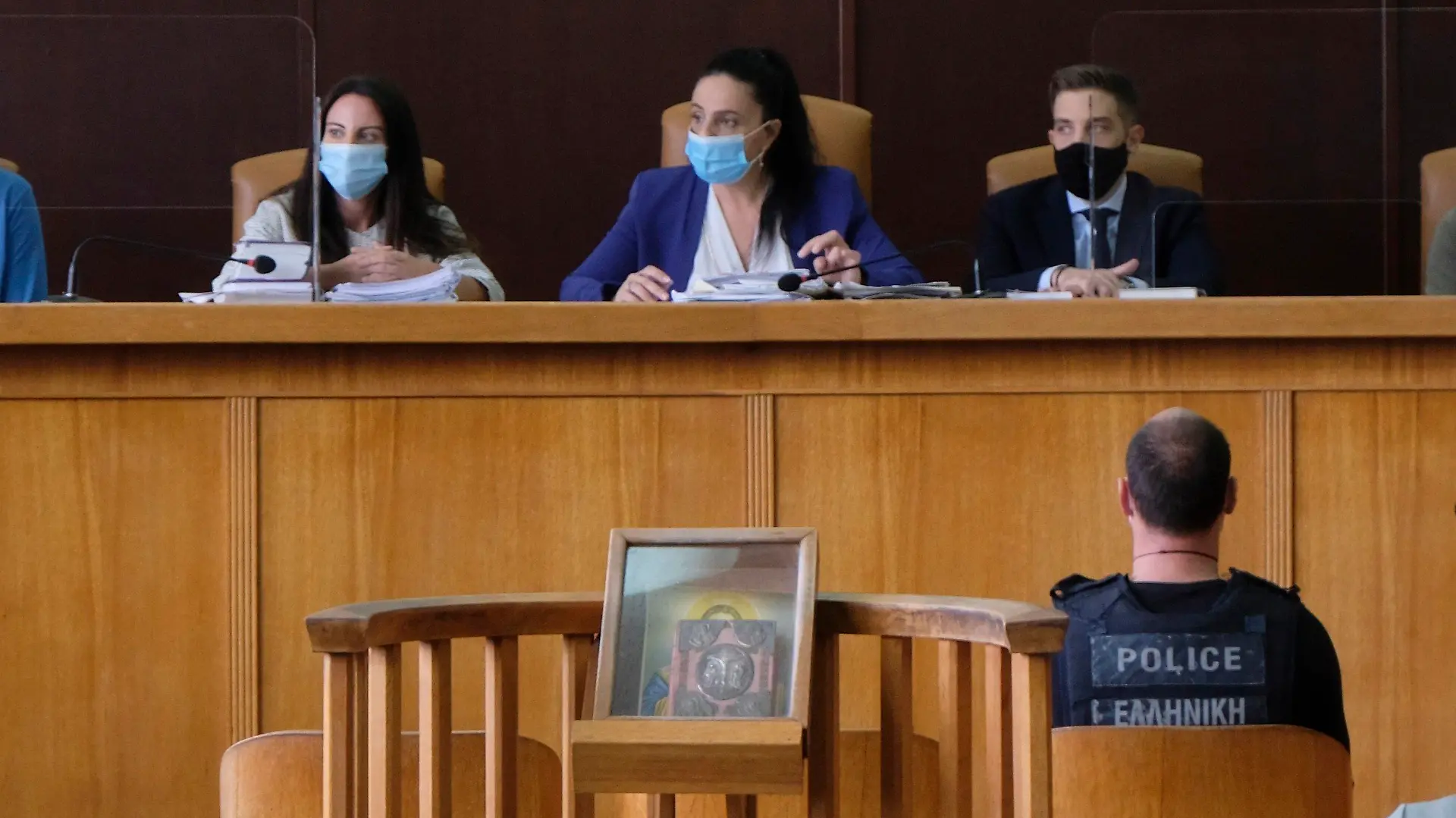Yiannis Paraskakis, bottom right, who accused of the brutal killing of American biologist Suzanne Eaton in 2019, wearing a bulletproof vest that reads "Greek Police", sits in the court room on the first day of the trial in Rethymno, on the Greek island of Crete, Tuesday, Oct. 13, 2020. Paraskakis has been charged with the rape and murder of Eaton, 59, who disappeared on July 2, 2019, while attending a conference near Chania and whose body was found six days later in an abandoned underground storage site used during World War II. (AP Photo/Giannis Angelakis)