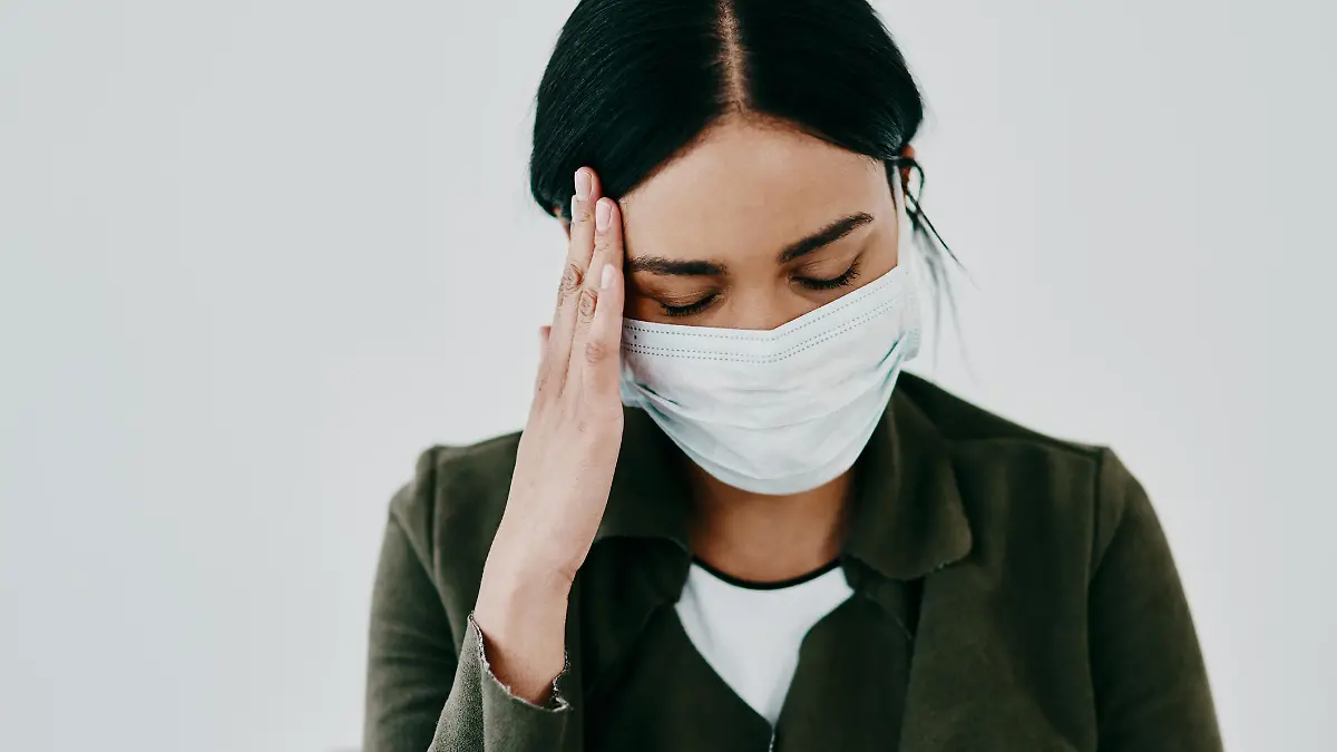 Frau mit Maske hat Kopfschmerzen