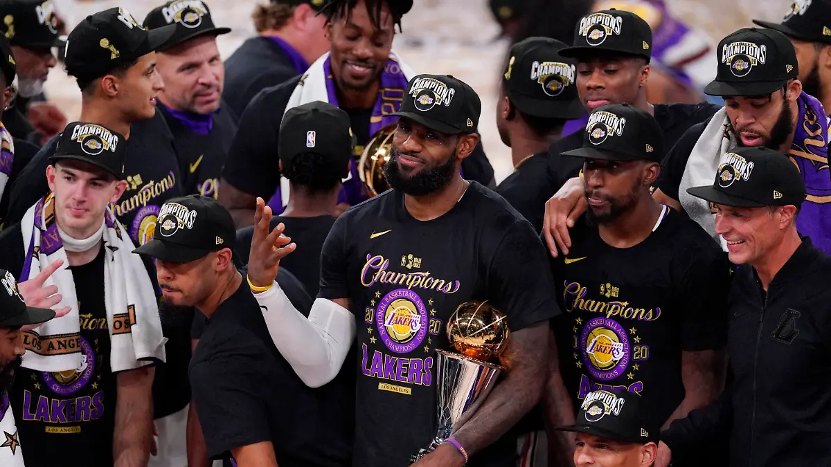 11.10.2020, USA, Lake Buena Vista: Basketball: NBA, Miami Heat - Los Angeles Lakers,Play-off-Runde, NBA-Finale, Finale, 6. Spieltag. LeBron James (M) von den Los Angeles Lakers hält die MVP-Trophäe, während er mit seinen Mannschaftskameraden den 17. NBA-Titel der Los Angeles Lakers feiert. James bekam zum vierten Mal in seiner Karriere die Auszeichnung als wertvollster Spieler der Finalserie (MVP). Foto: Mark J. Terrill/AP/dpa +++ dpa-Bildfunk +++