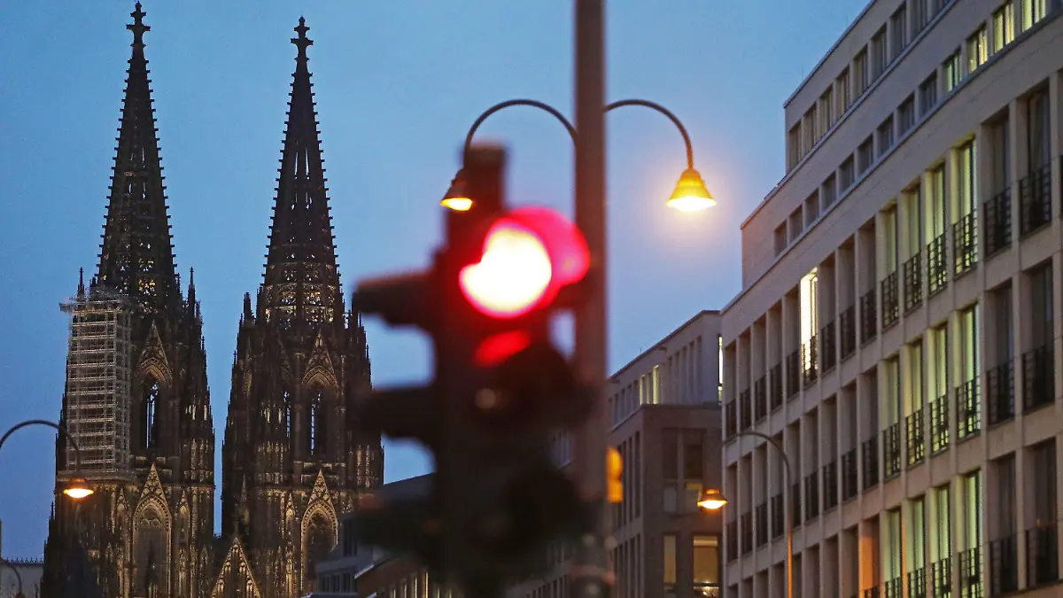 09.10.2020, Nordrhein-Westfalen, Köln: Eine Ampel steht am Dom (l) auf Rot. Mit Köln und Essen liegen zwei nordrhein-westfälische Großstädte in der Corona-Pandemie nur noch ganz knapp unter der wichtige Warnstufe von 50 Neuinfektionen pro 100 000 Einwohner in sieben Tagen. Foto: Oliver Berg/dpa +++ dpa-Bildfunk +++