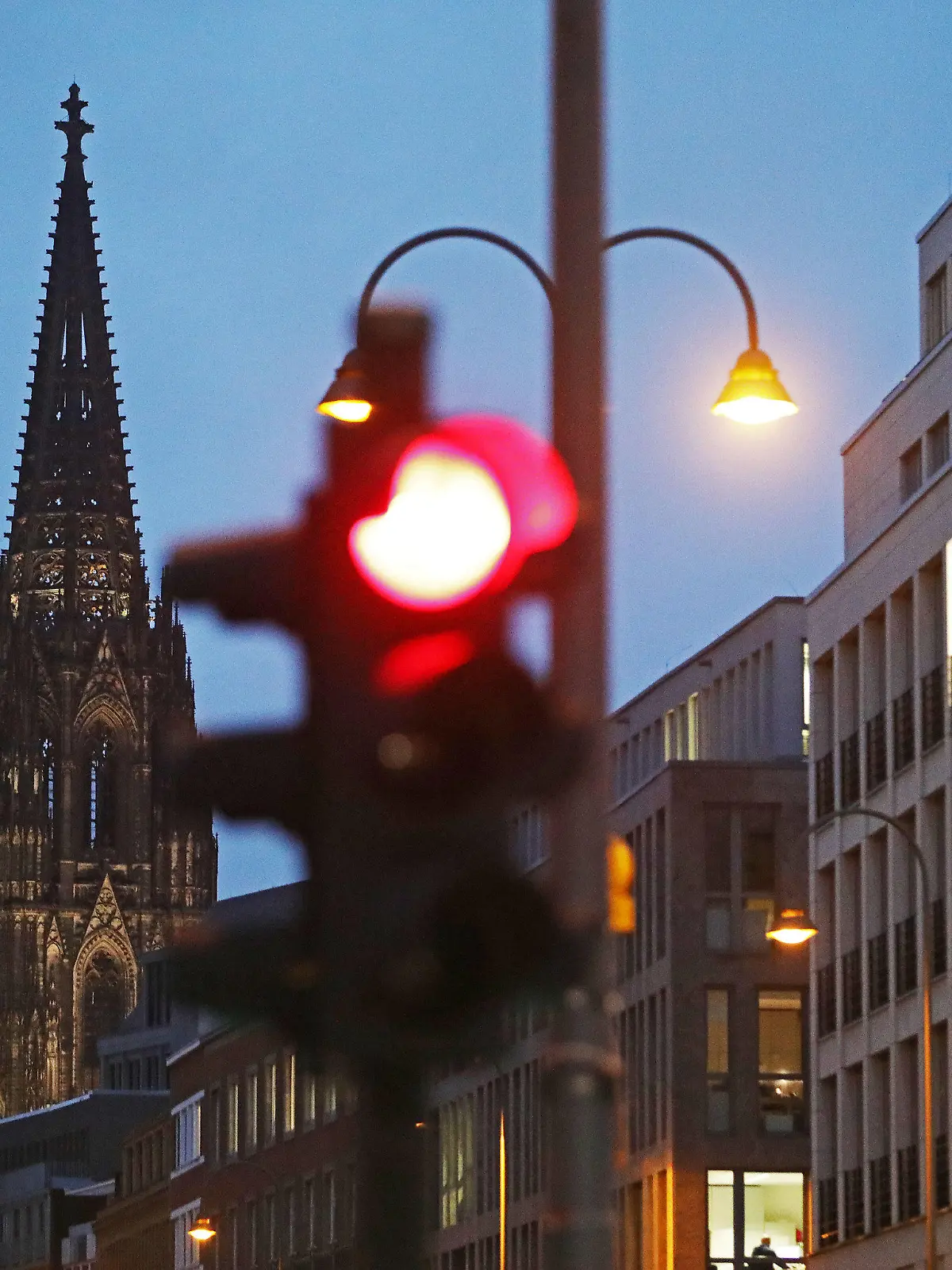 09.10.2020, Nordrhein-Westfalen, Köln: Eine Ampel steht am Dom (l) auf Rot. Mit Köln und Essen liegen zwei nordrhein-westfälische Großstädte in der Corona-Pandemie nur noch ganz knapp unter der wichtige Warnstufe von 50 Neuinfektionen pro 100 000 Einwohner in sieben Tagen. Foto: Oliver Berg/dpa +++ dpa-Bildfunk +++