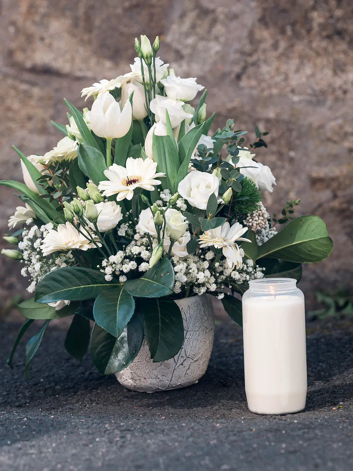 06.04.2023, Bayern, Wunsiedel: Ein Strauß Blumen und eine Kerze wurden von U. Scharf (nicht im Bild, CSU), Staatsministerin für Familie, Arbeit und Soziales, an einer Mauer vor dem Kinder- und Jugendhilfezentrum niedergelegt. Ein zehnjähriges Mädchen war in dem Kinder- und Jugendhilfezentrum aufgefunden worden. Das Kind ist nach Einschätzung der Staatsanwaltschaft gewaltsam ums Leben gekommen. Foto: Daniel Vogl/dpa +++ dpa-Bildfunk +++