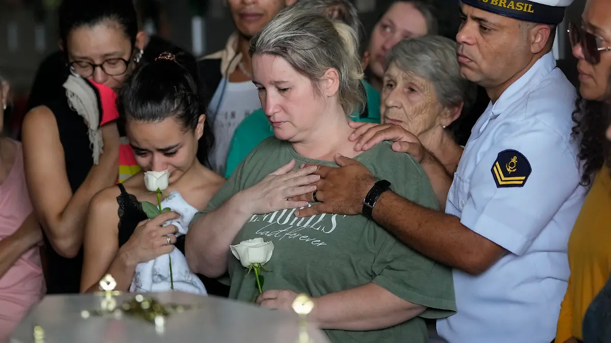 Bruno Machado, right, and his wife Neide Cunha, center, attend the funeral of their five-year-old son Bernardo who was killed by a man with a hatchet inside a day care center, at the Sao Jose cemetery in Blumenau, Santa Catarina state, Brazil, Thursday, April 6, 2023. A man with a hatchet jumped over a wall and burst into a day care center Wednesday in Brazil, killing four children, authorities said. (AP Photo/Andre Penner)