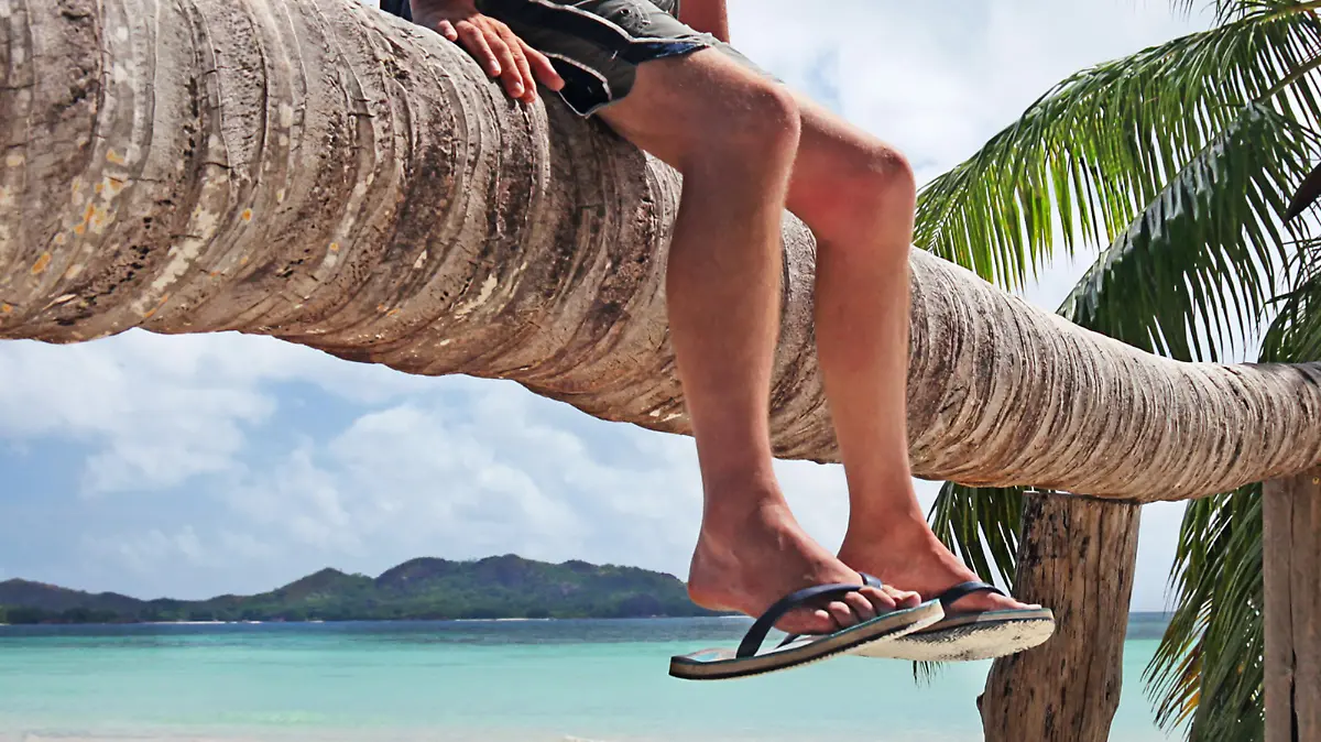 Mann mit Sandalen im Trend am Strand.