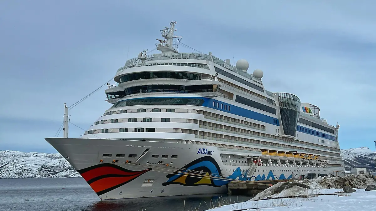 Das Kreuzfahrtschiff Aida mar liegt Karfreitag 2023 im Hafen von Alta (Norwegen). Der restliche Schnee des endenden Winters türmt sich vor dem Kreuzfahrtriesen.
