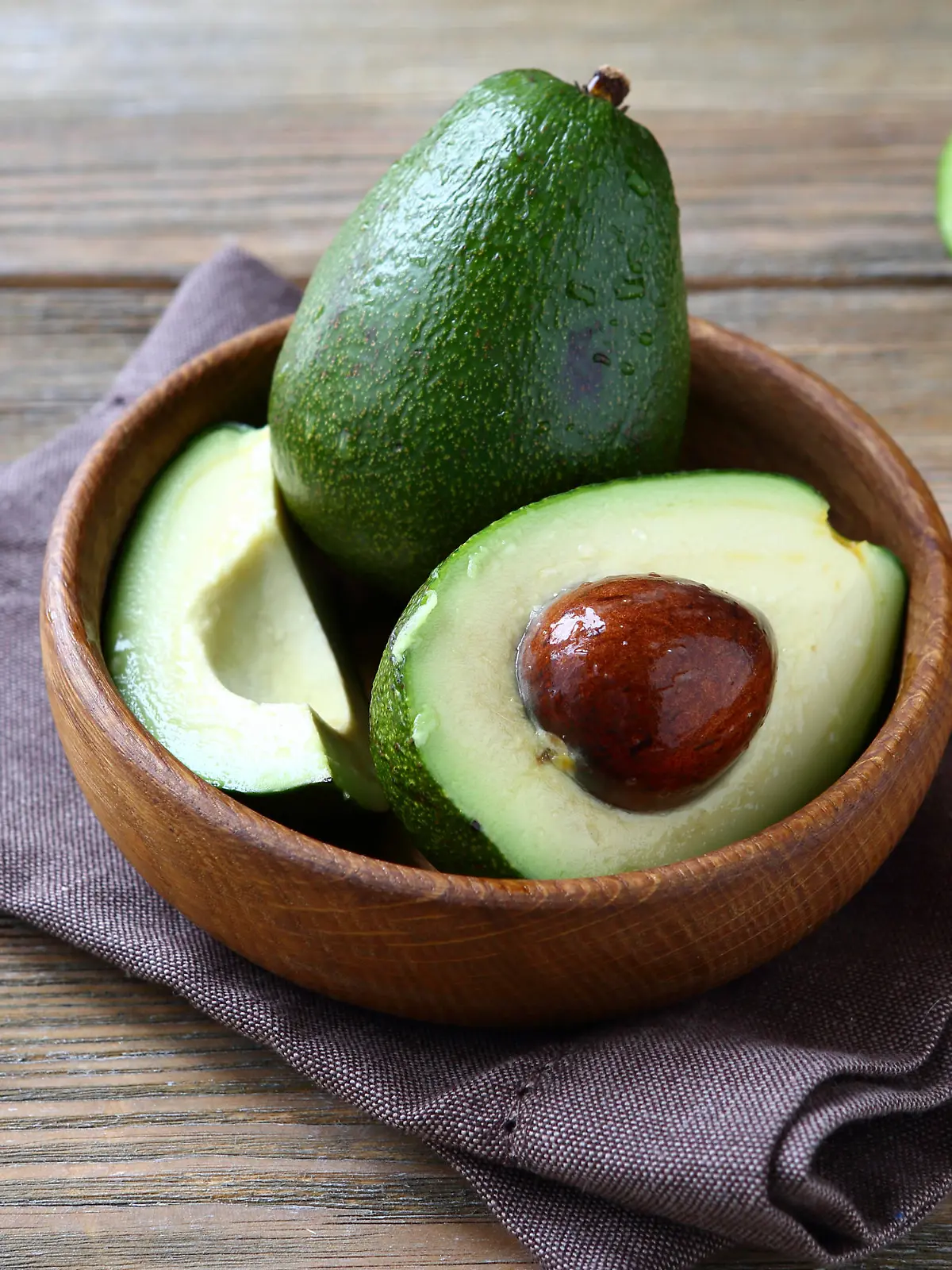 Avocado whole and halves, healthy food on a wooden boards