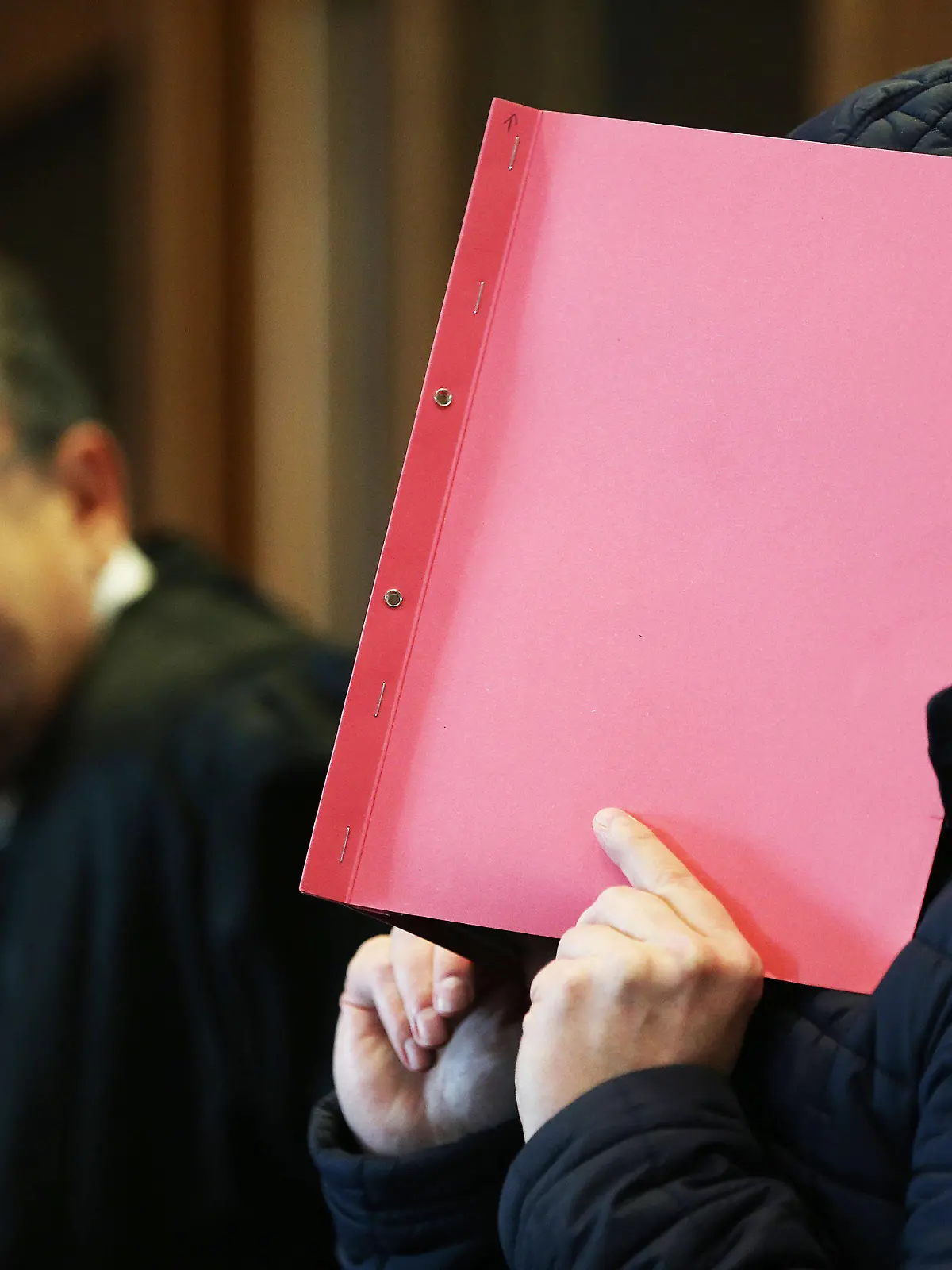 06.10.2020, Nordrhein-Westfalen, Köln: Der Angeklagte (r) im Prozess wegen schweren sexuellen Missbrauchs von Kindern sitzt Gerichtssaal, während er sich eine Mappe vor das Gesicht hält. Im Hintergrund sitzt der Anwalt des Angeklagten. Im Missbrauchskomplex Bergisch Gladbach ist der Angeklagte zu zwölf Jahren Haft verurteilt worden. Foto: Oliver Berg/dpa +++ dpa-Bildfunk +++