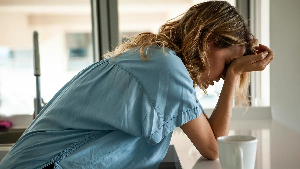 Potrait of stressed woman with head in hands standing indoors during daytime