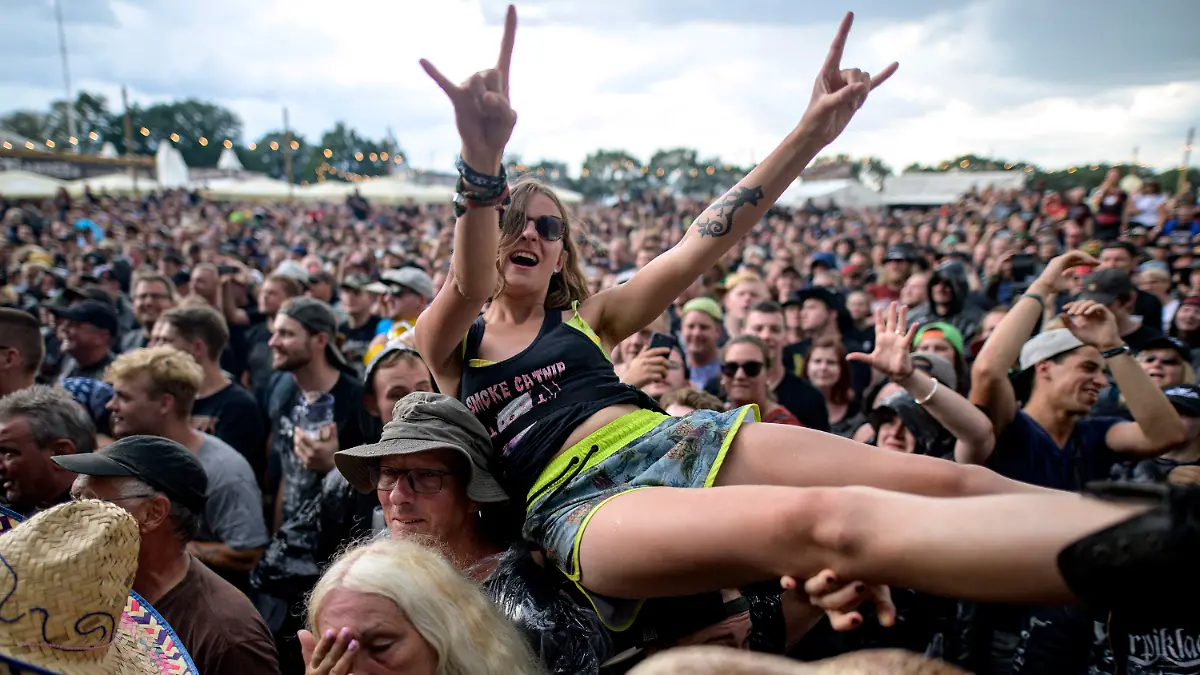 31.07.2019, Schleswig-Holstein, Wacken: Besucher des Wacken Open Air feiern beim Auftritt der Feuerwehrkapelle Wacken. Das Konzert der Firefighters musste nach einer Unwetterwarnung abgebrochen werden. Foto: Axel Heimken/dpa +++ dpa-Bildfunk +++