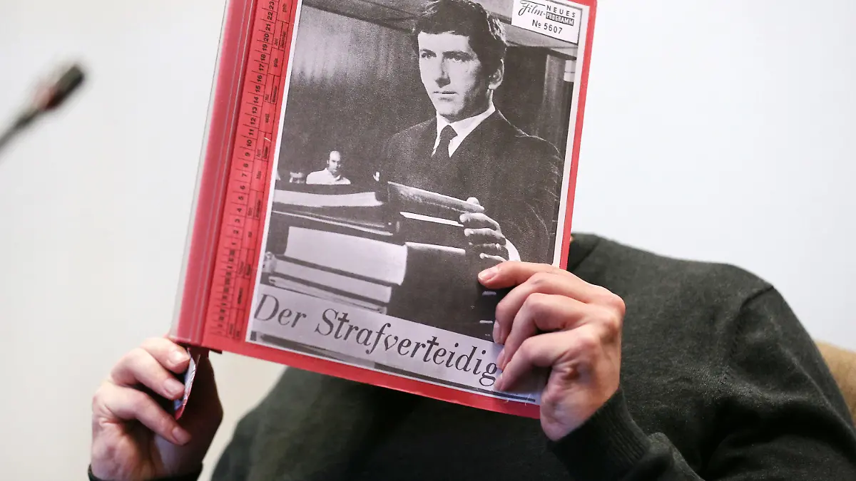 ARCHIV - 17.08.2020, Nordrhein-Westfalen, Köln: Der Angeklagte sitzt zu Beginn eines Prozesstages wegen schweren sexuellen Missbrauchs von Kindern im Gerichtssaal, während er sich eine Mappe mit aufgeklebten Fotos von Filmszenen des Films «Der Strafverteidiger» vor das Gesicht hält. (zu dpa: «Fall Bergisch Gladbach: Angeklagter berichtet über eigenen Missbrauch») Foto: Oliver Berg/dpa - ACHTUNG: Nur zur redaktionellen Verwendung im Zusammenhang mit einer Berichterstattung über den Prozess im Missbrauchsfall Bergisch Gladbach und nur mit vollständiger Nennung des vorstehenden Credits +++ dpa-Bildfunk +++