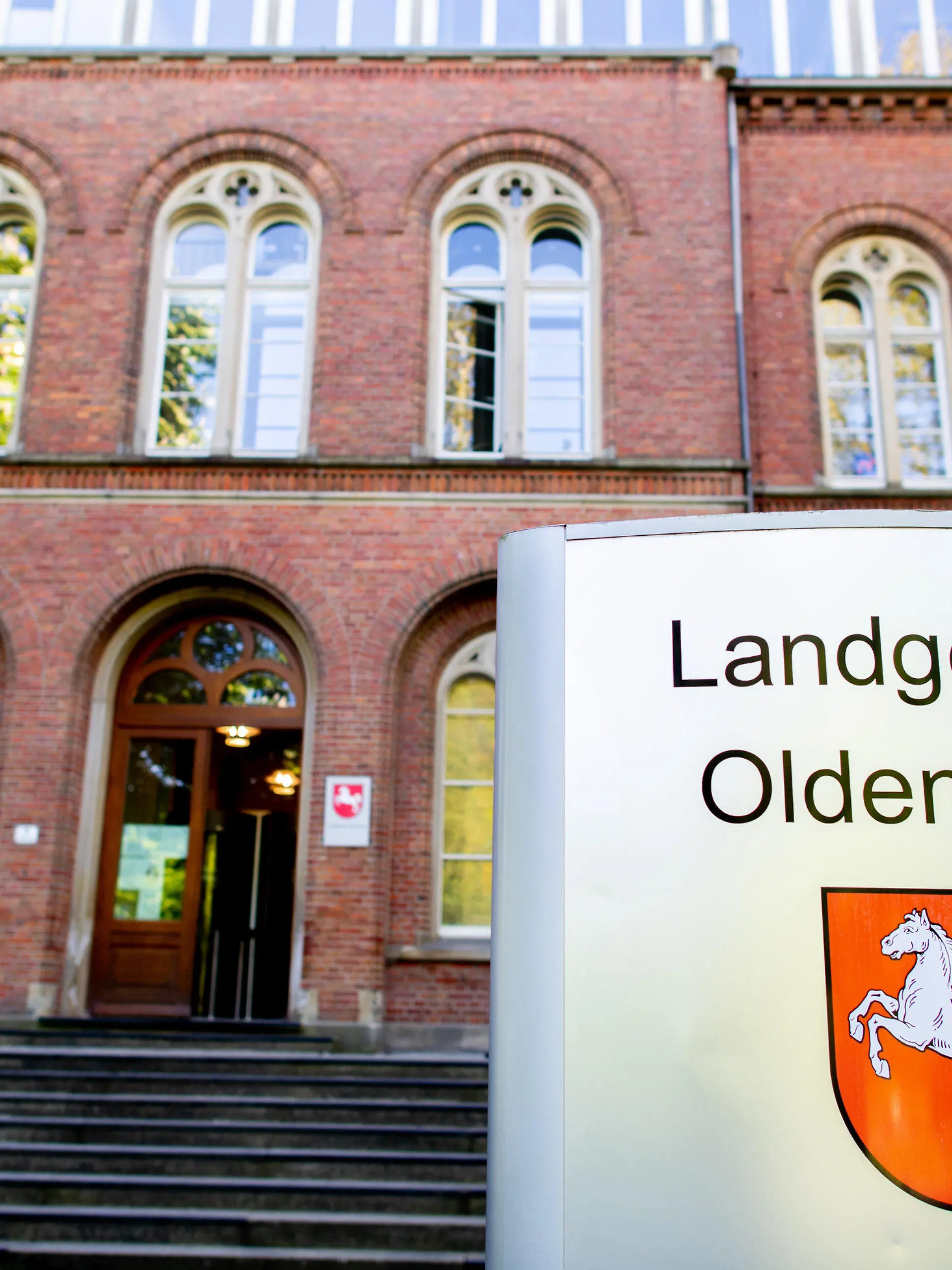 09.05.2022, Niedersachsen, Oldenburg: Ein Schild mit dem niedersächsischen Landeswappen steht vor dem Eingang zum Landgericht Oldenburg, wo ein Prozess wegen zweifachen Mordes fortgesetzt wird. Der angeklagte Mann soll im Oktober 2021 in Delmenhorst zunächst in einer Bar einen vermeintlichen Nebenbuhler erstochen haben. Anschließend verletzte er seine Lebensgefährtin mit einem Messer so stark, dass sie zwei Tage später starb. Foto: Hauke-Christian Dittrich/dpa +++ dpa-Bildfunk +++