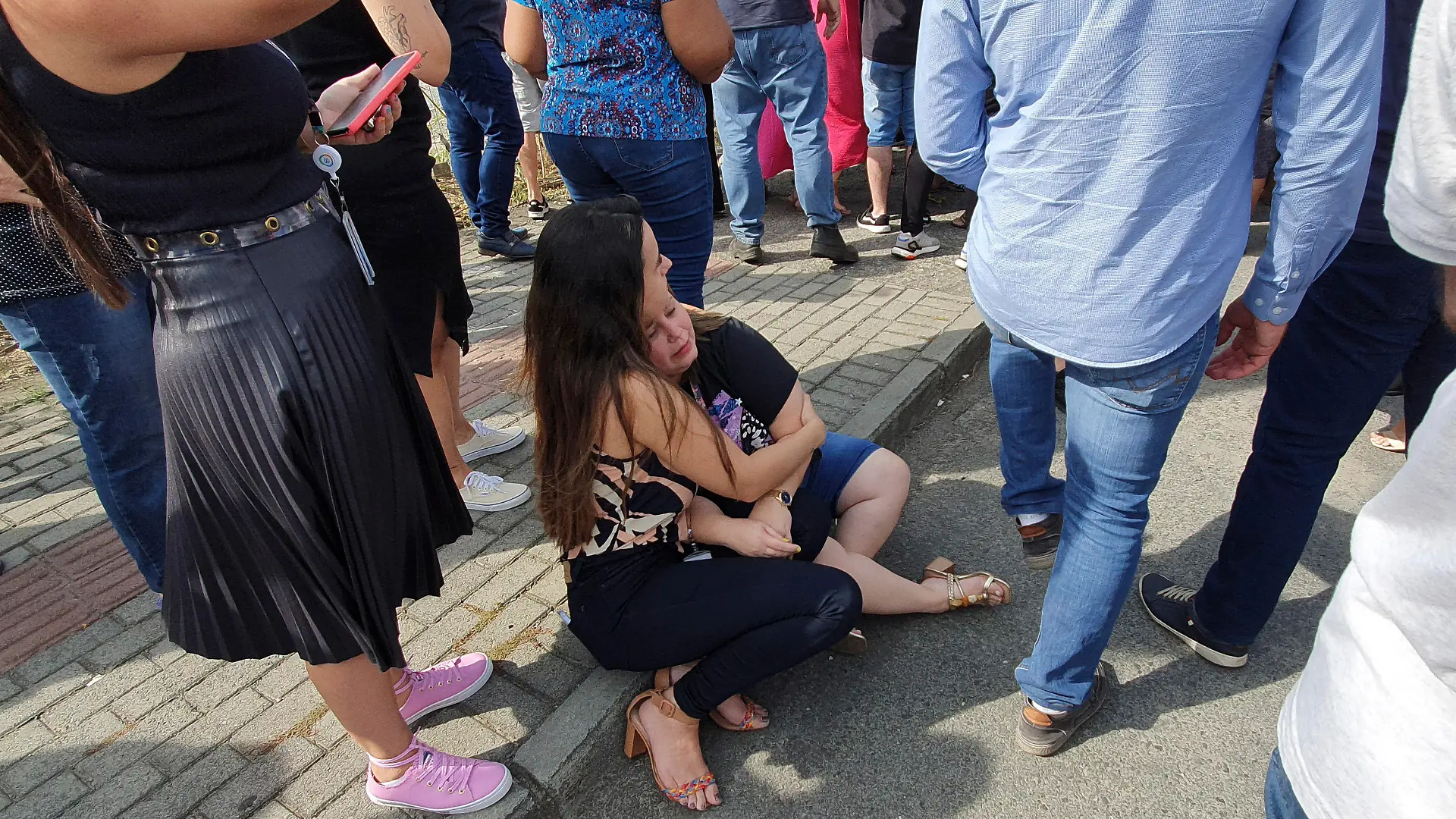 05.04.2023, Brasilien, Blumenau: Eine Frau und ein Mädchen sitzen vor der Kinderkrippe «Cantinho do Bom Pastor» nach einem tödlichen Angriff. Ein 25-Jähriger war nach Angaben der Militärpolizei am Mittwochmorgen in die private Kinderkrippe in Blumenau, das von deutschen Einwanderern gegründet und geprägt wurde, eingedrungen und hatte Kinder angegriffen. Foto: Patrick Rodrigues/POrtal NSC Total/dpa +++ dpa-Bildfunk +++