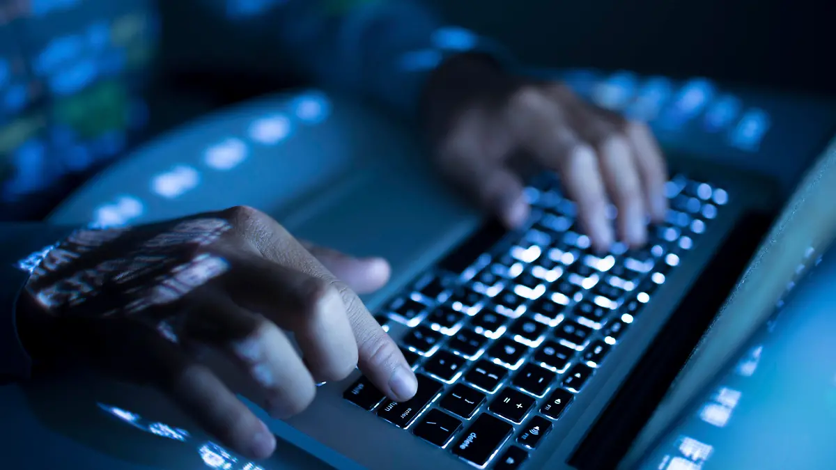 Close-up image of coder typing on computer
