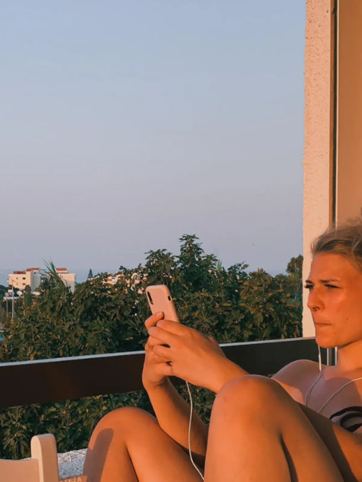 Frau sitzt auf Balkon im roten Abendlicht