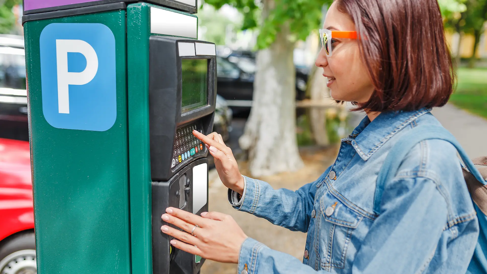 Eine junge Frau nutzt einen Parkautomaten.