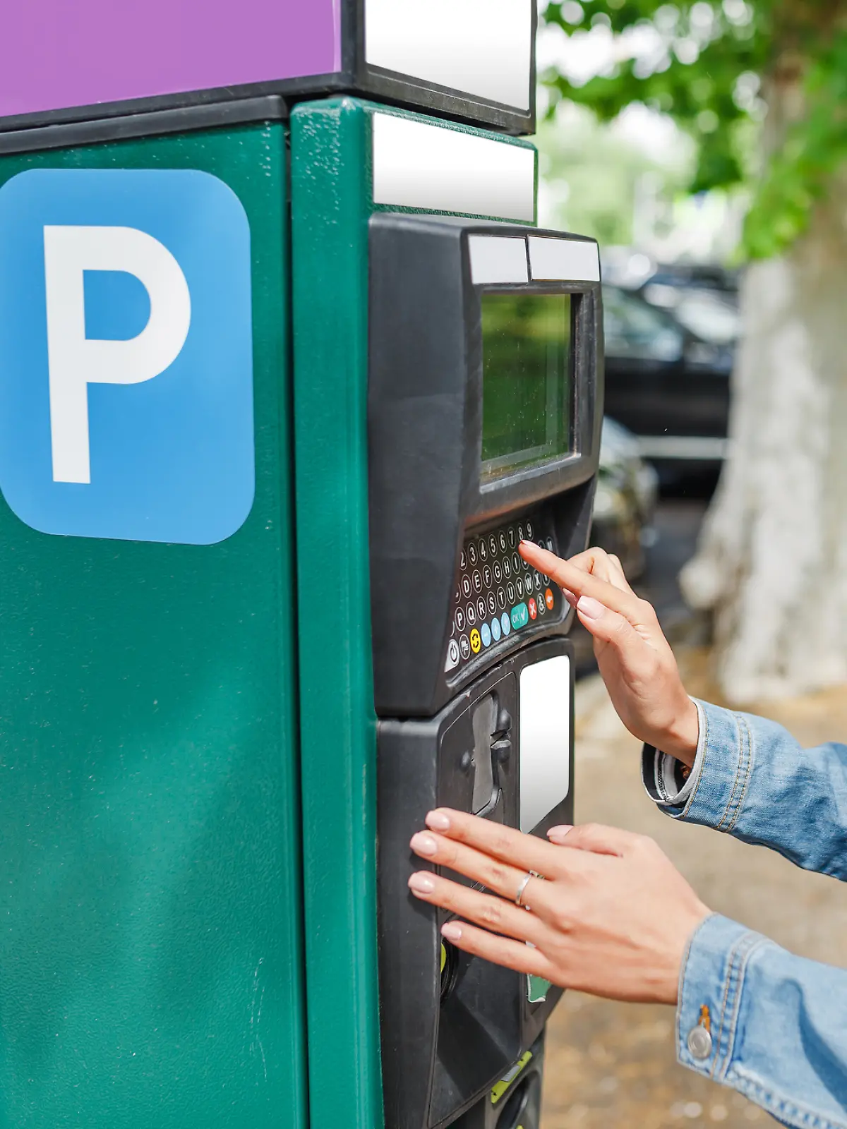 Eine junge Frau nutzt einen Parkautomaten.