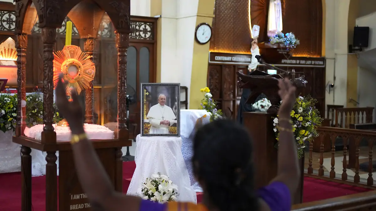 Eine Frau betet vor einem Porträt von Papst Franziskus in einer Kirche in Colombo