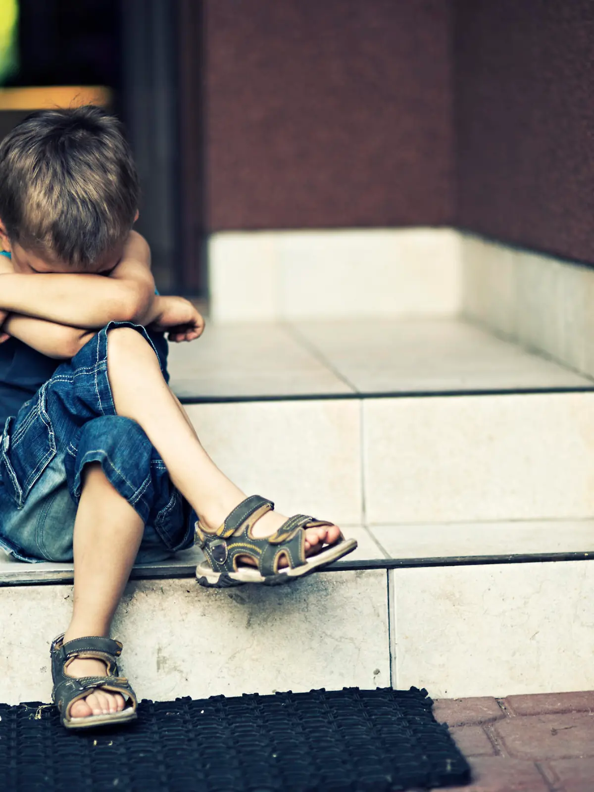 Depressed child sitting on stairs.