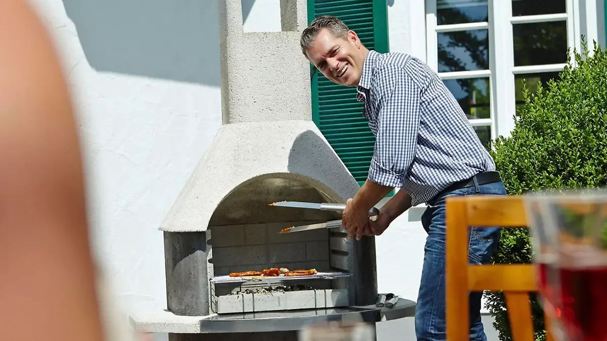 Mann, der am Grill steht.