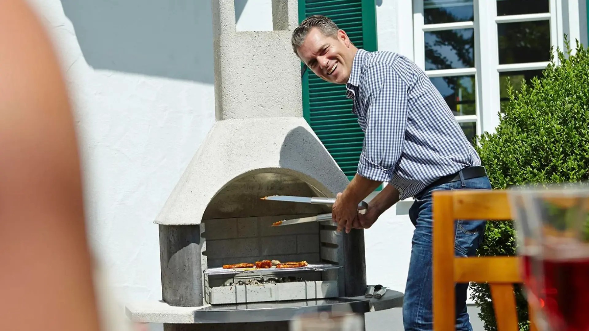 Mann, der am Grill steht.