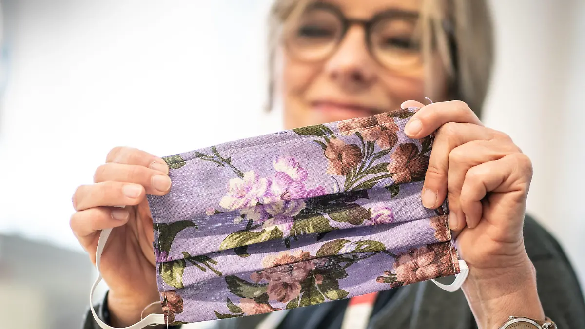24.03.2020, Hessen, Frankfurt/Main: Fachanleiterin Kerstin Jentschke vom "Cariteam" der Caritas Frankfurt zeigt ihre soeben fertig gestellte Mundschutzmaske. Zur Zeit näht sie mit ihren Kolleginnen die auskochbaren Masken aus bunten Baumwollstoffen selbst. Diese werden zum Beispiel dringend in der Altenpflege benötigt . Normalerweise können im "Cariteam" Langzeitarbeitslose, Asylbewerber oder Geflüchtete berufliche Erfahrungen sammeln. Foto: Frank Rumpenhorst/dpa +++ dpa-Bildfunk +++