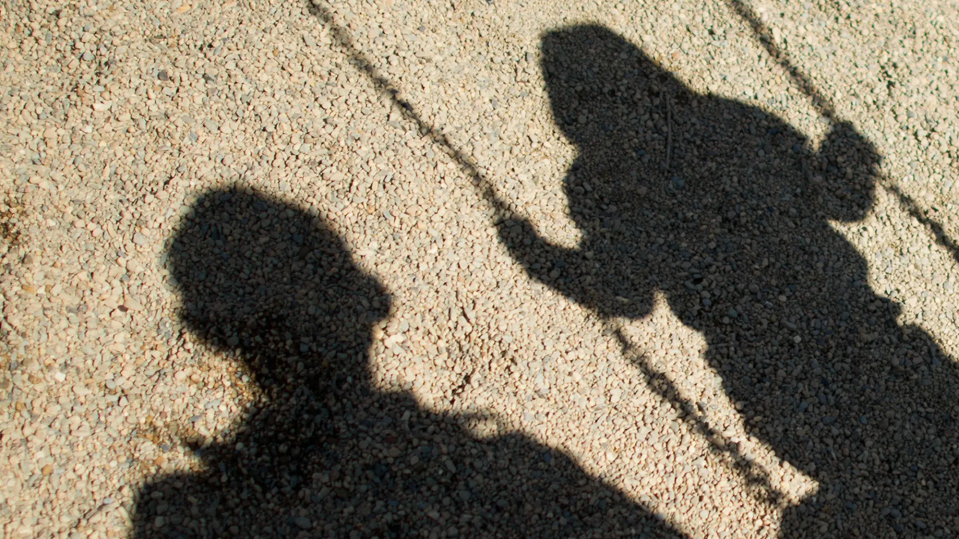 ARCHIV - Der Schatten von einem Mann und einem schaukelnden Kind fallen am 27.08.2014 auf Sand auf einem Spielplatz in Braunschweig (Niedersachsen). Dank der aufsehenerregenden öffentlichen Fahndung mit Missbrauchsfotos eines vierjährigen Mädchens haben die Ermittler einen 24-Jährigen aus dem niedersächsischen Landkreis Wesermarsch festgenommen. (zu dpa «Fahndungserfolg in Missbrauchsfall: 24-jähriger Mann festgenommen» vom 10.10.2017) Foto: Julian Stratenschulte/dpa +++(c) dpa - Bildfunk+++