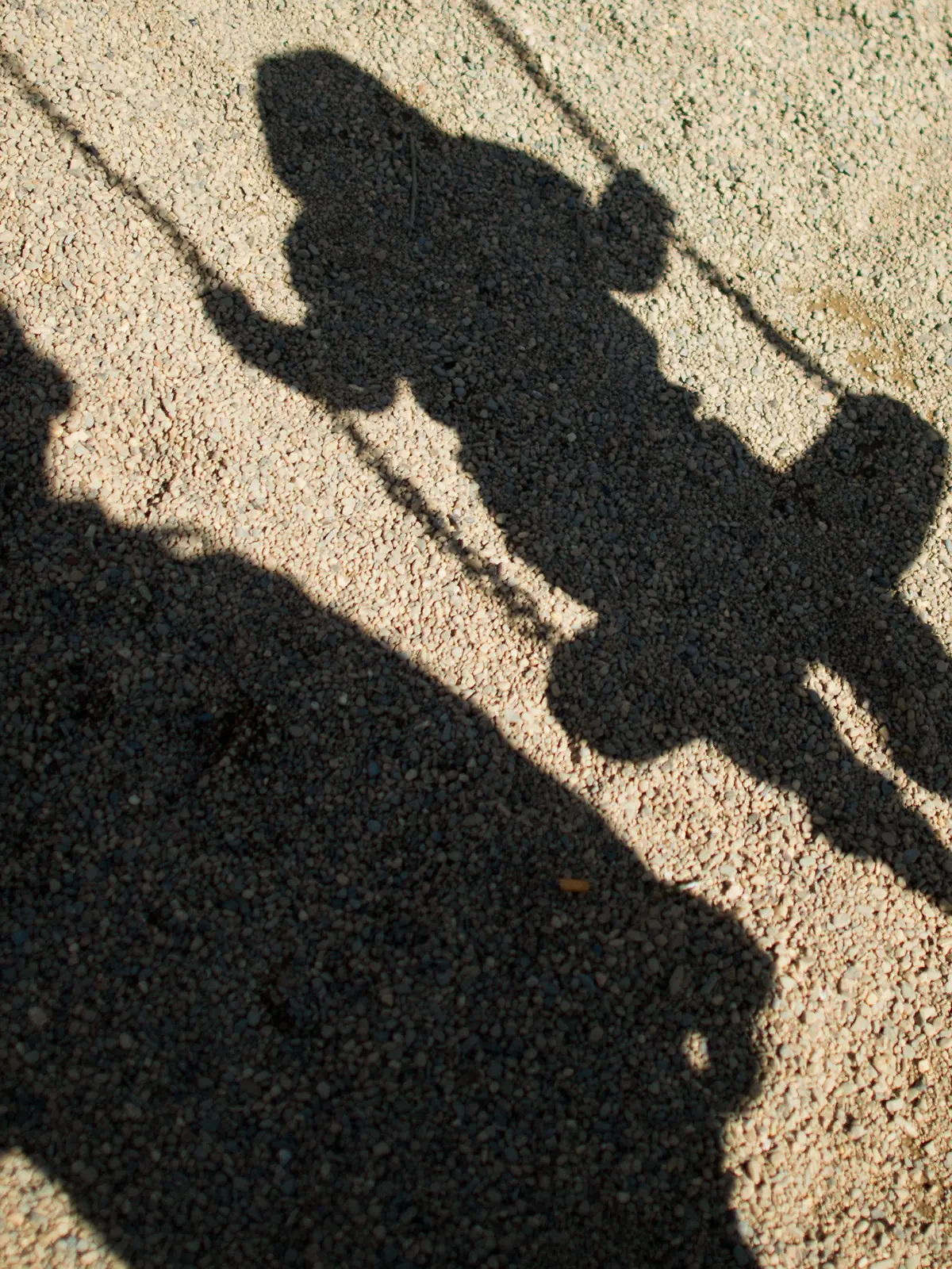 ARCHIV - Der Schatten von einem Mann und einem schaukelnden Kind fallen am 27.08.2014 auf Sand auf einem Spielplatz  in Braunschweig (Niedersachsen). Dank der aufsehenerregenden öffentlichen Fahndung mit Missbrauchsfotos eines vierjährigen Mädchens haben die Ermittler einen 24-Jährigen aus dem niedersächsischen Landkreis Wesermarsch festgenommen. (zu dpa «Fahndungserfolg in Missbrauchsfall: 24-jähriger Mann festgenommen» vom 10.10.2017) Foto: Julian Stratenschulte/dpa +++(c) dpa - Bildfunk+++