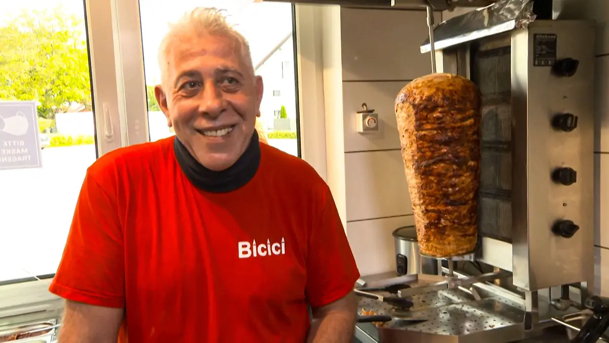 Hüseyin Bicici steht in seinem Laden neben einem Spieß