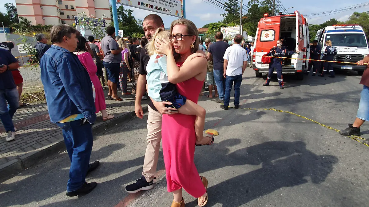 A woman conforts a crying girl outside the daycare center "Cantinho do Bom Pastor" after a fatal attack on children in Blumenau, Santa Catarina state, Brazil, Wednesday, April 5, 2023. A man with a hatchet jumped over a wall and invaded the daycare center, killing four children and wounding at least five others, authorities said. (Patrick Rodrigues/Portal NSC Total via AP)