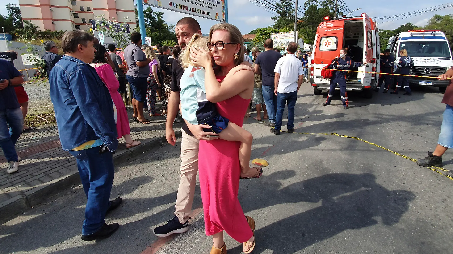 A woman conforts a crying girl outside the daycare center "Cantinho do Bom Pastor" after a fatal attack on children in Blumenau, Santa Catarina state, Brazil, Wednesday, April 5, 2023. A man with a hatchet jumped over a wall and invaded the daycare center, killing four children and wounding at least five others, authorities said. (Patrick Rodrigues/Portal NSC Total via AP)