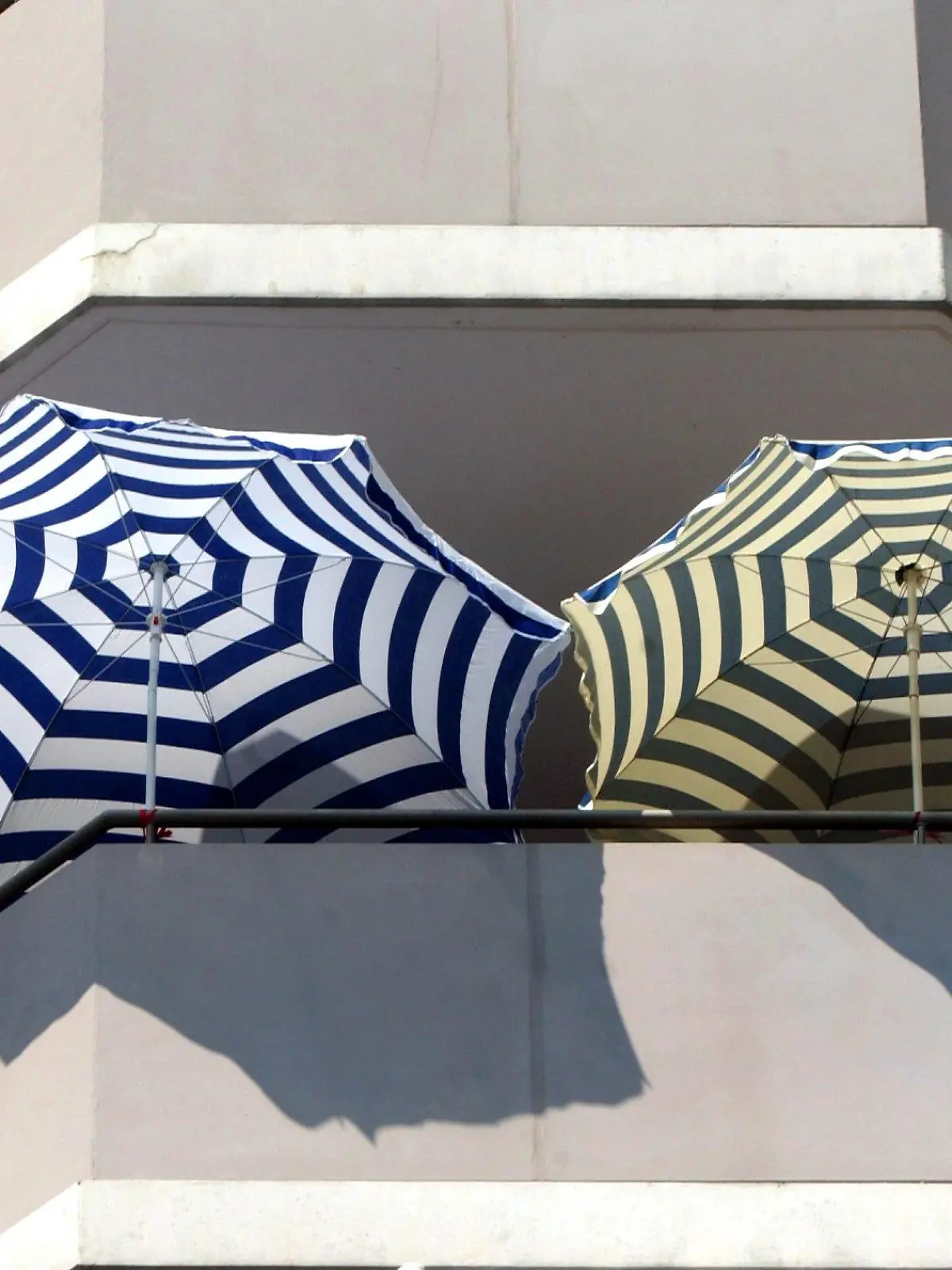 Sonnenschirme stehen am 30.07.2003 auf einem Balkon in Berlin Lichtenberg. "Urlaub auf Balkonien" hat eine lange Tradition. Schon in den 30er Jahren wurde in Berlin "Balkonien" besungen. Auf den wenigen Quadratmetern selbstbestimmter Grünfläche ist alles wichtige nur ein paar Schritt weit entfernt - Entspannung ohne Eingwöhnstress. Bei den alten Römern hatte der Balkon noch eine repräsentative Funktion für Kurzauftritte der Herrschenden vor dem Volk, in Kriesenzeiten avancierte er zum kleinen Gemüsegarten. Seit 1956 wurden Balkone in der Bundesrepublik per Gesetz für neugebaute Sozialwohnungen Standart und mittlerweile drückt das Freiluftraucherzimmer ein Stück Lebensqualität in der Stadt aus.