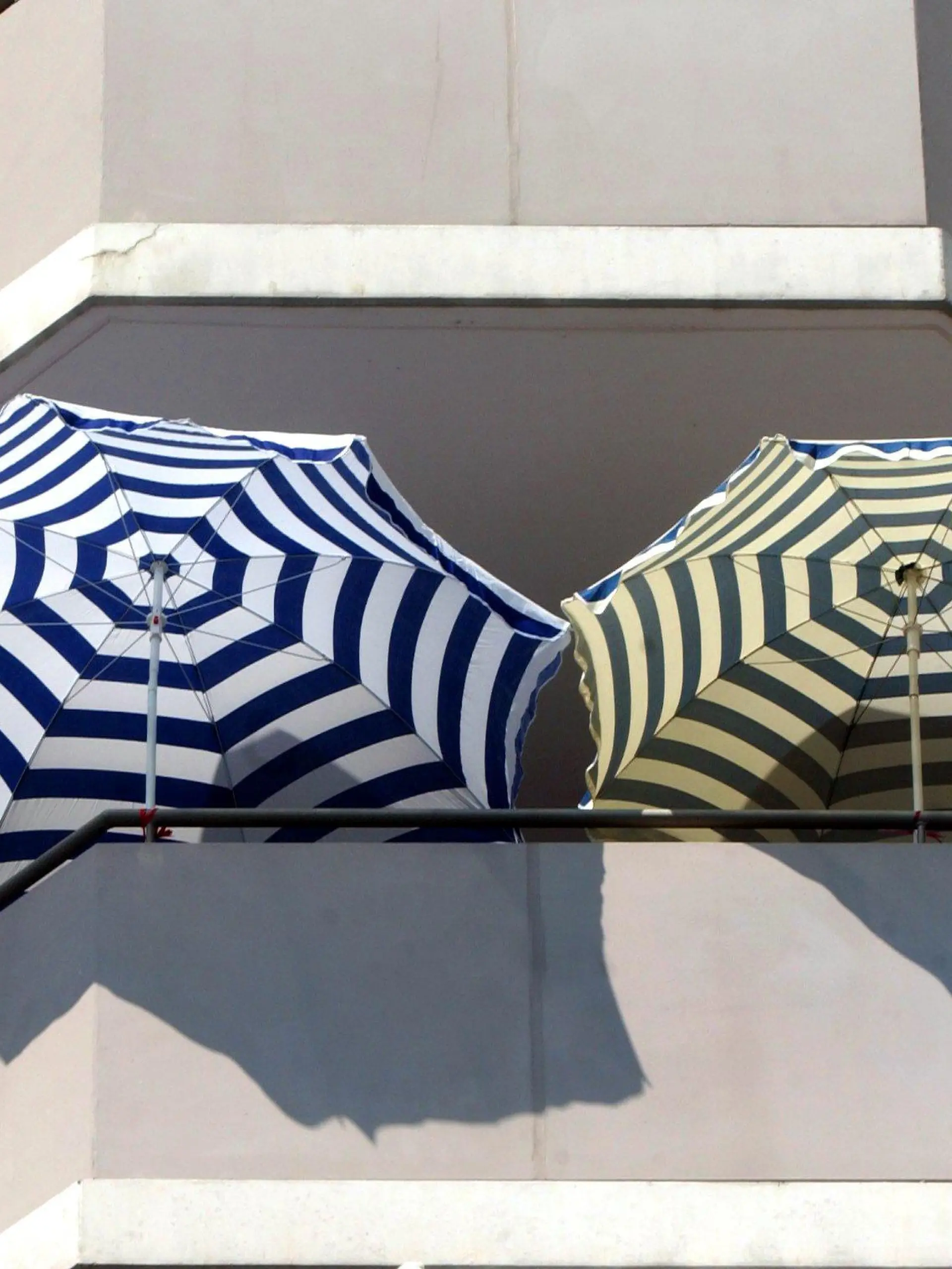 Sonnenschirme stehen am 30.07.2003 auf einem Balkon in Berlin Lichtenberg. "Urlaub auf Balkonien" hat eine lange Tradition. Schon in den 30er Jahren wurde in Berlin "Balkonien" besungen. Auf den wenigen Quadratmetern selbstbestimmter Grünfläche ist alles wichtige nur ein paar Schritt weit entfernt - Entspannung ohne Eingwöhnstress. Bei den alten Römern hatte der Balkon noch eine repräsentative Funktion für Kurzauftritte der Herrschenden vor dem Volk, in Kriesenzeiten avancierte er zum kleinen Gemüsegarten. Seit 1956 wurden Balkone in der Bundesrepublik per Gesetz für neugebaute Sozialwohnungen Standart und mittlerweile drückt das Freiluftraucherzimmer ein Stück Lebensqualität in der Stadt aus.