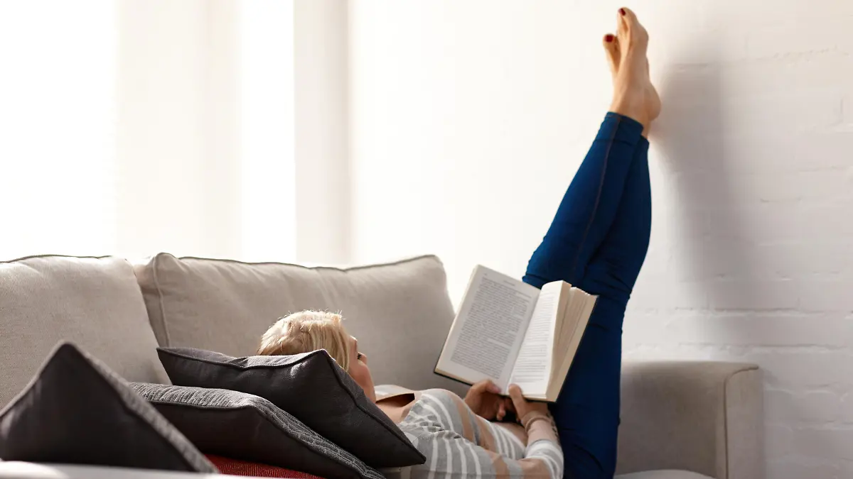 Mature woman relaxing on sofa reading a novel at home