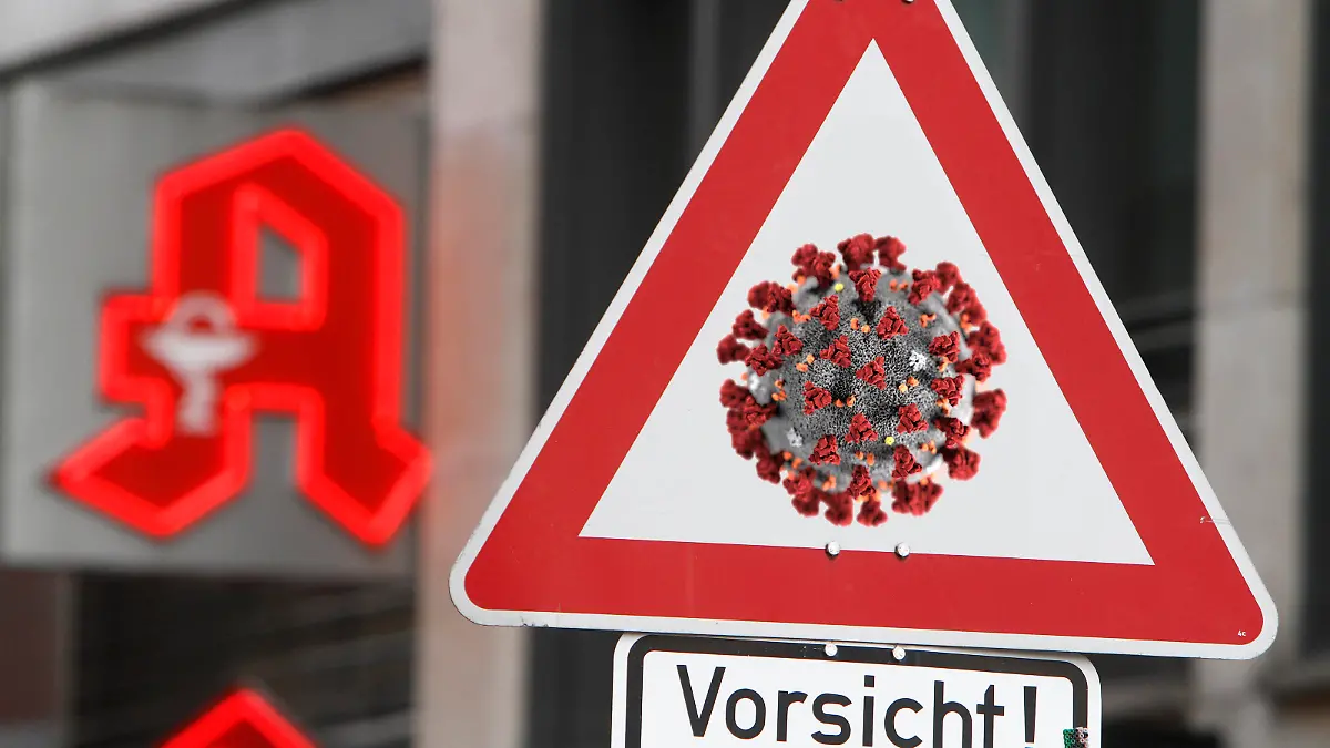 Fotomontage Symbolbild zur Ausbreitung des Coronavirus und der öffentliche Umgang mit der Krankheit: Verkehrsschild Achtung Coronavirus mit Zusatz Vorsicht vor dem Logo einer Apotheke in Frankfurt, Hessen, Deutschland *** Photomontage symbolic image of the spread of the coronavirus and the public handling of the disease Traffic sign Attention Coronavirus with the addition of Caution before the logo of a pharmacy in Frankfurt, Hesse, Germany