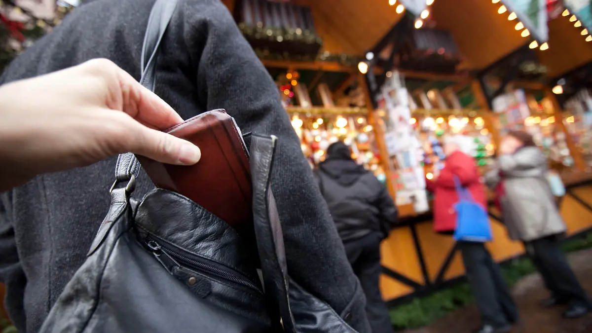 ARCHIV - ILLUSTRATION - Ein Mann zieht am 10.12.2009 auf dem Weihnachtsmarkt in Frankfurt am Main einer Besucherin die Geldbörse aus der Handtasche (gestelltes Bild - Illustration). (zu dpa «Taschendiebe mögen Weihnachtsmärkte - Polizei warnt und gibt Tipps» vom 03.12.2016) +++(c) dpa - Bildfunk+++