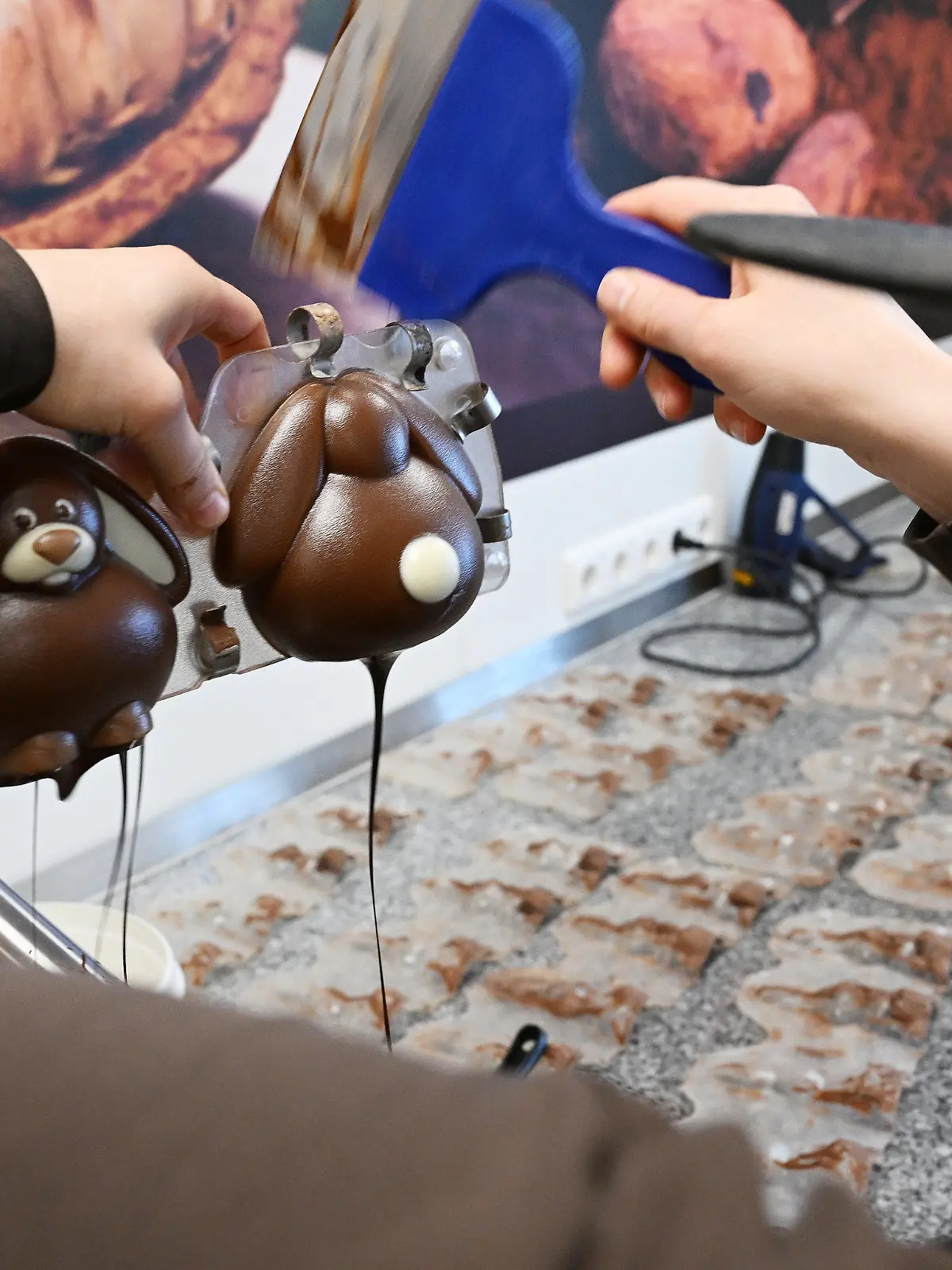 PRODUKTION - 30.03.2023, Bayern, Garmisch-Partenkirchen: Ein Konditorin gießt in der Chocolaterie Amelie eine «geschminkte» Osterhasen-Form mit Schokolade aus. Die Herstellung von Schoko-Osterhasen oder Schoko-Ostereiern ist hier in jedem Arbeitsschritt noch Handarbeit. (zu dpa: «Schokolade trotzt der Krisenstimmung - Fast 10 Kilo pro Kopf genascht») Foto: Angelika Warmuth/dpa +++ dpa-Bildfunk +++