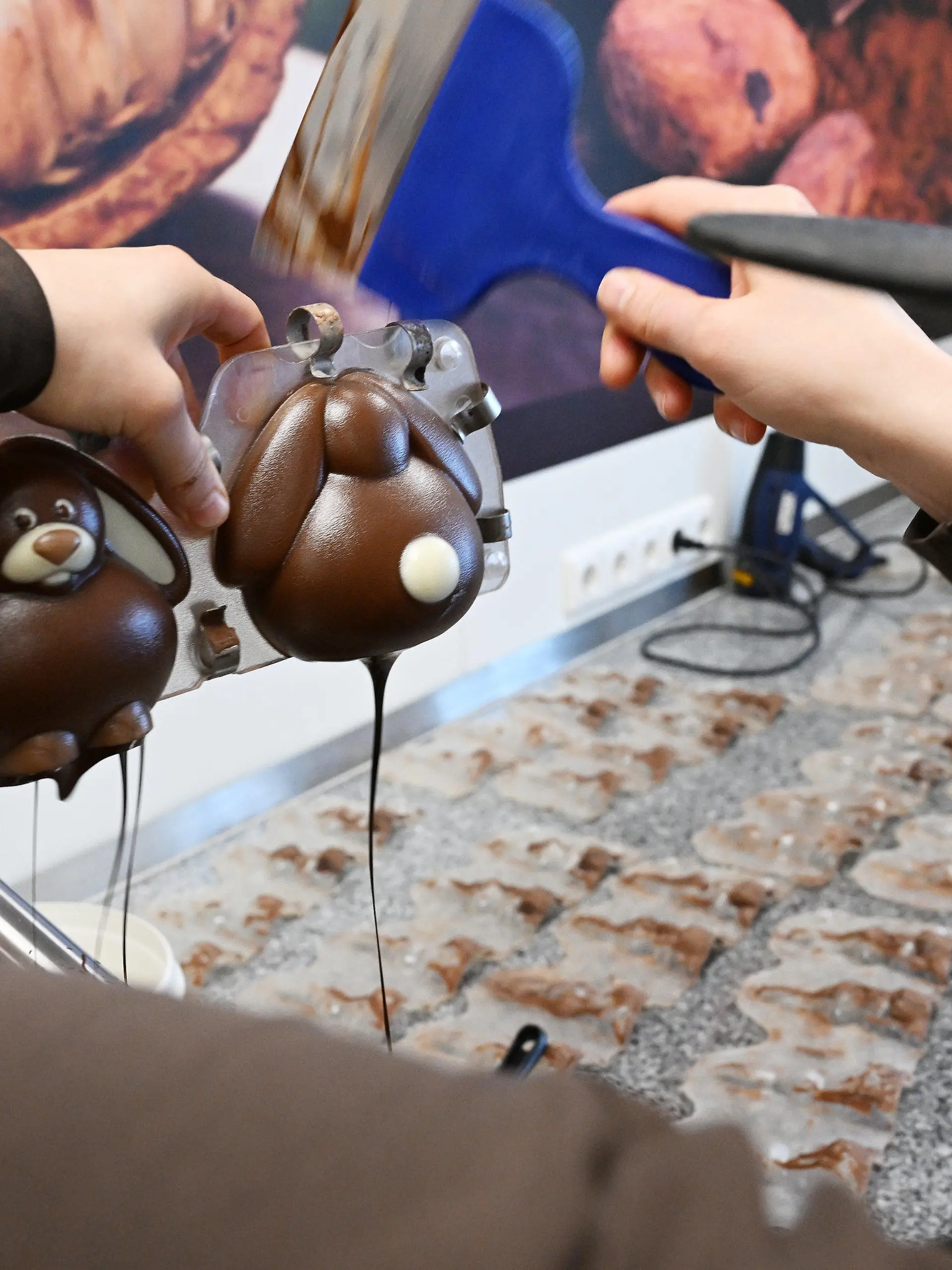 PRODUKTION - 30.03.2023, Bayern, Garmisch-Partenkirchen: Ein Konditorin gießt in der Chocolaterie Amelie eine «geschminkte» Osterhasen-Form mit Schokolade aus. Die Herstellung von Schoko-Osterhasen oder Schoko-Ostereiern ist hier in jedem Arbeitsschritt noch Handarbeit. (zu dpa: «Schokolade trotzt der Krisenstimmung - Fast 10 Kilo pro Kopf genascht») Foto: Angelika Warmuth/dpa +++ dpa-Bildfunk +++