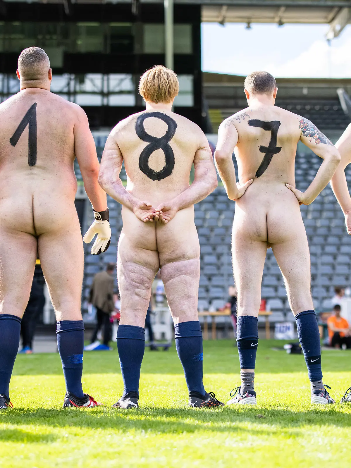 06.09.2020, Nordrhein-Westfalen, Wuppertal: Nackte Fußballer aus Deutschland stehen mit auf den Rücken gemalten Zahlen vor dem Spiel im Stadion am Zoo nebeneinander. Aus Protest gegen die aus ihrer Sicht zunehmende Kommerzialisierung des Profifußballs traten zwei Mannschaften nackt gegeneinander an. Organisator des Naked Fußball ist der Künstler Starczewski, der jeden Teilnehmer im Anschluss per Urkunde zum offiziellen Nacktionalspieler ernennen will. Foto: Marcel Kusch/dpa +++ dpa-Bildfunk +++