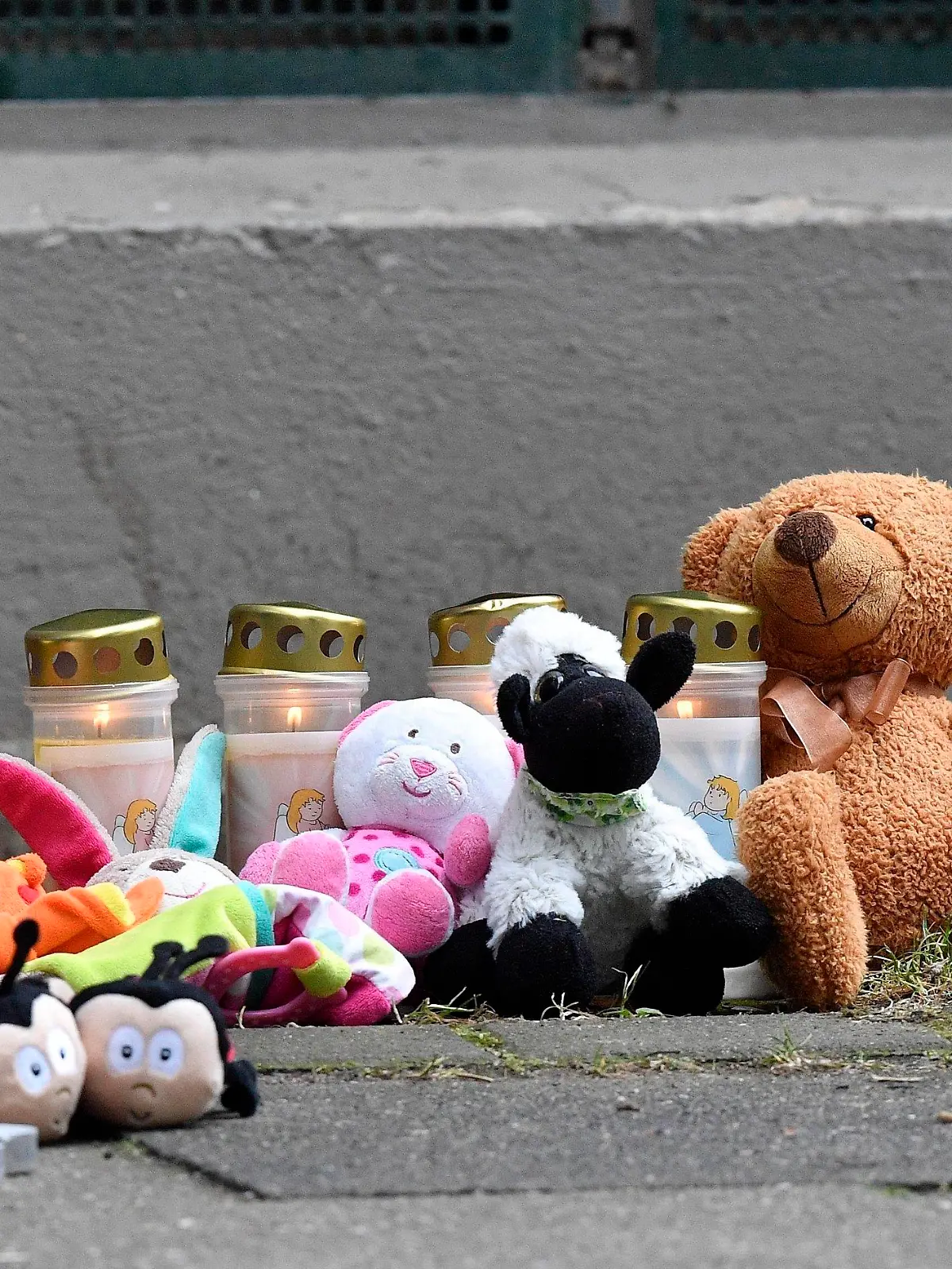 Teddy bears and candles are pictured in front of an apartment building where five dead children were found in Solingen, Germany, Friday, Sept. 4, 2020. Police say five young children have been found dead on Thursday at the apartment in Solingen, their mother is suspected of killing them. Police said the children's 27-year-old mother later jumped in front of a train in Duesseldorf and was taken to a hospital with injuries. Only one child of the mother survived, who was send to his grandmother before. (AP Photo/Martin Meissner)