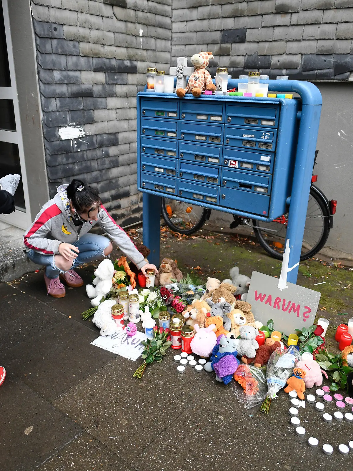 04.09.2020, Nordrhein-Westfalen, Solingen: Eine Frau legt zum Gedenken an die toten Kinder Blumen und Kerzen an einem Briefkasten ab. In einer Wohnung des Hauses wurden fünf tote Kinder gefunden. Ihre Mutter soll sie getötet und dann einen Suizidversuch unternommen haben. Foto: Roberto Pfeil/dpa - ACHTUNG: Namenschilder auf dem Briefkasten wurden aus persönlichkeitsrechtlichen Gründen gepixelt. +++ dpa-Bildfunk +++