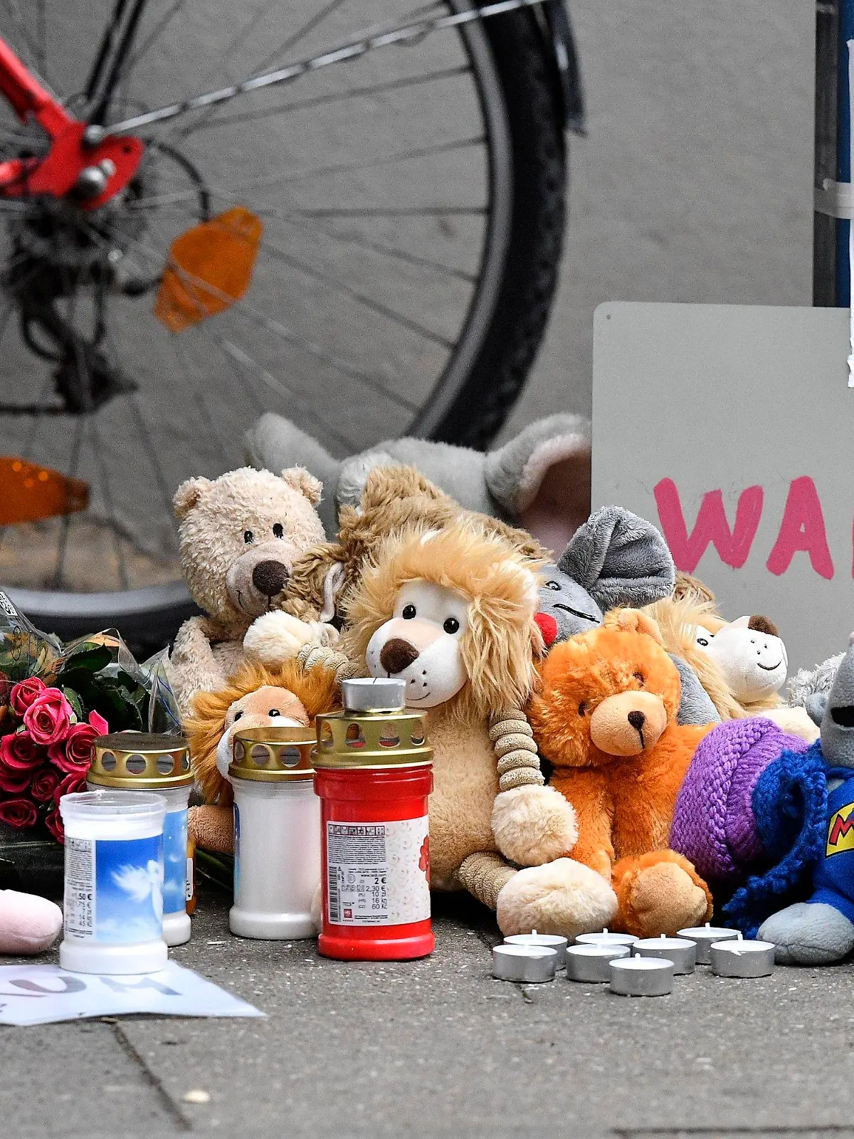 Teddy bears and candles are pictured at the entrance of an apartment building where five dead children were found in Solingen, Germany, Friday, Sept. 4, 2020. A sign reads "Why?". Police say five young children have been found dead on Thursday at the apartment in Solingen, their mother is suspected of killing them. Police said the children's 27-year-old mother later jumped in front of a train in Duesseldorf and was taken to a hospital with injuries. Only one child of the mother survived, who was send to his grandmother before. (AP Photo/Martin Meissner)