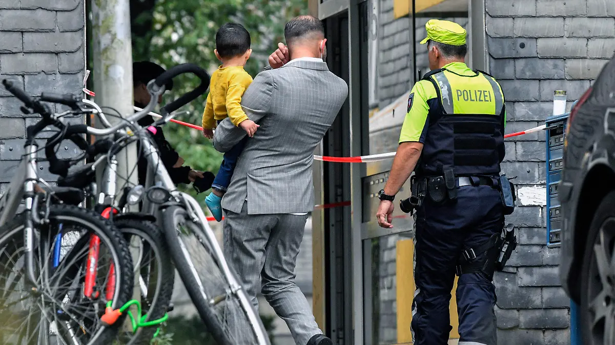 Residents enter a house with a police officer, where five dead children were found in Solingen, Germany, Thursday, Sept. 3, 2020. Police say the five children have been found dead at an apartment in the western German city, and their mother is suspected of killing them. (AP Photo/Martin Meissner)