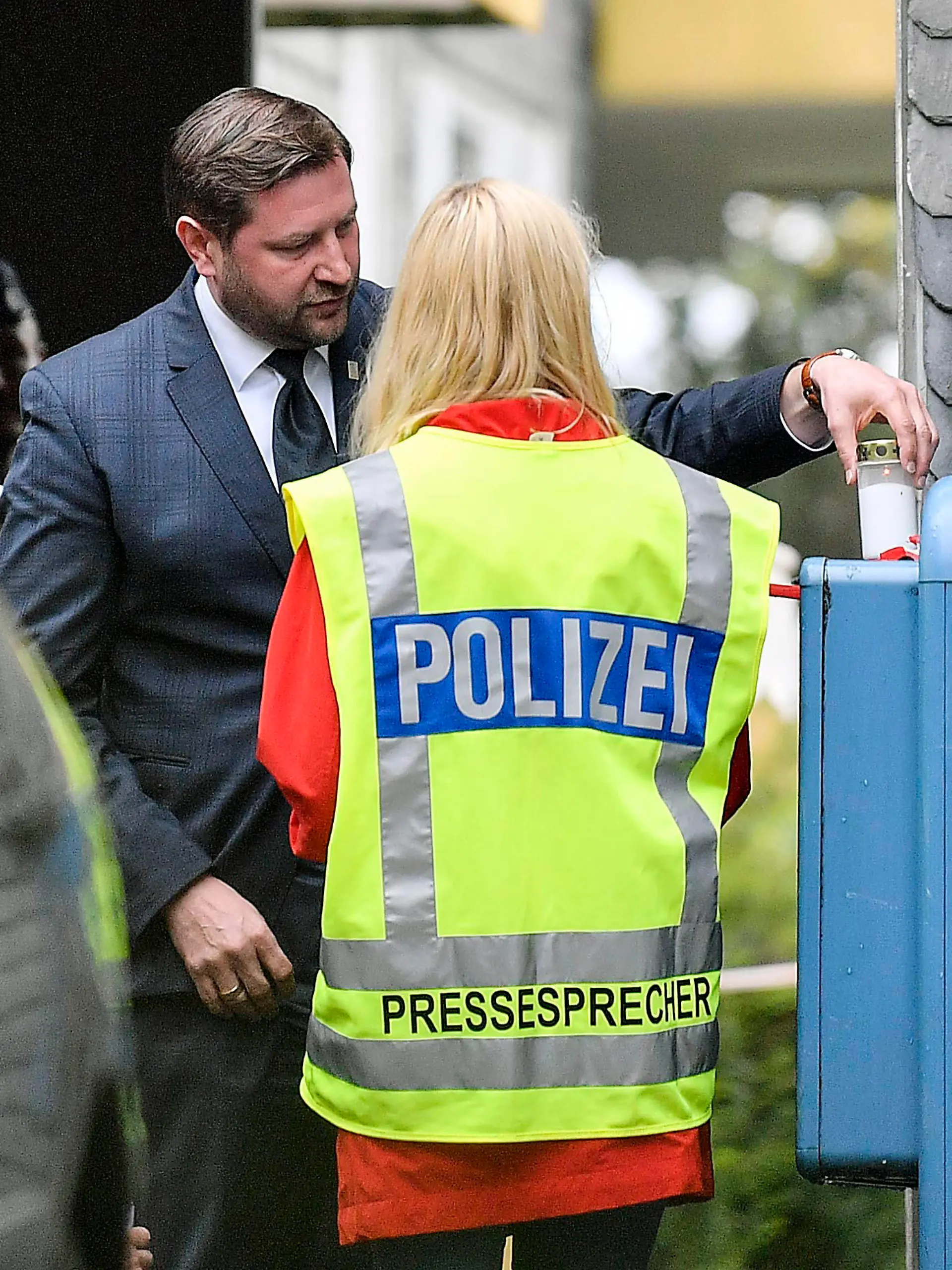 Solingen's mayor Tim Kurzbach puts a candle at the entrance of the house, where five dead children were found in Solingen, Germany, Thursday, Sept. 3, 2020. Police say five children have been found dead at an apartment in a western German city, and their mother is suspected of killing them. The bodies of three girls and two boys were found in Solingen, near Cologne and Duesseldorf on Thursday. (AP Photo/Martin Meissner)