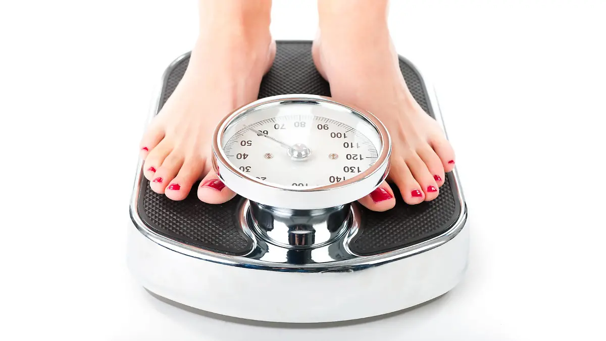 Diet and weight, young woman standing on a scale, only feet to be seen