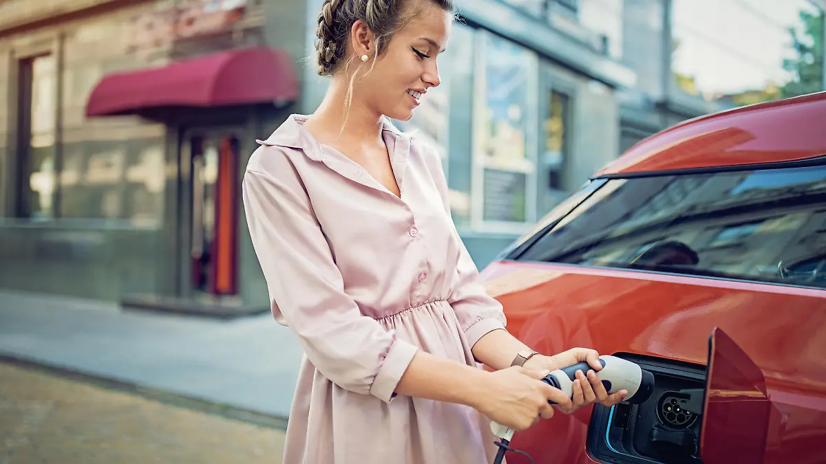 Young girl is charging her electric car in the city