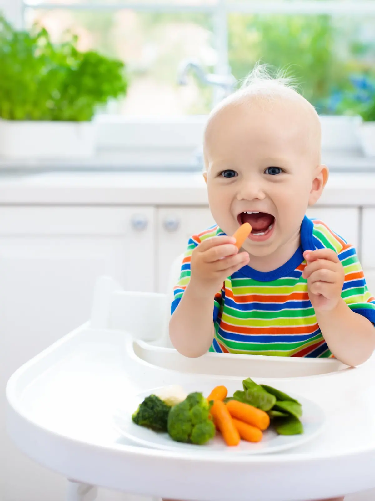Fröhliches Baby isst Gemüse