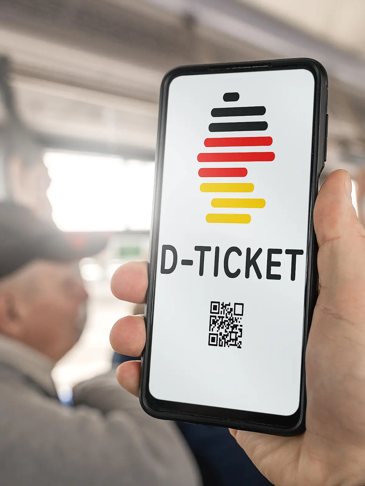 31 March 2023: Germany Ticket on a smartphone. A man holding a smartphone on a bus with the D-Ticket logo app FOTOMONTAGE *** Deutschland Ticket auf einem Smartphone. Ein Mann hält ein Smartphone in einem Bus in der Hand mit dem D-Ticket Logo App FOTOMONTAGE