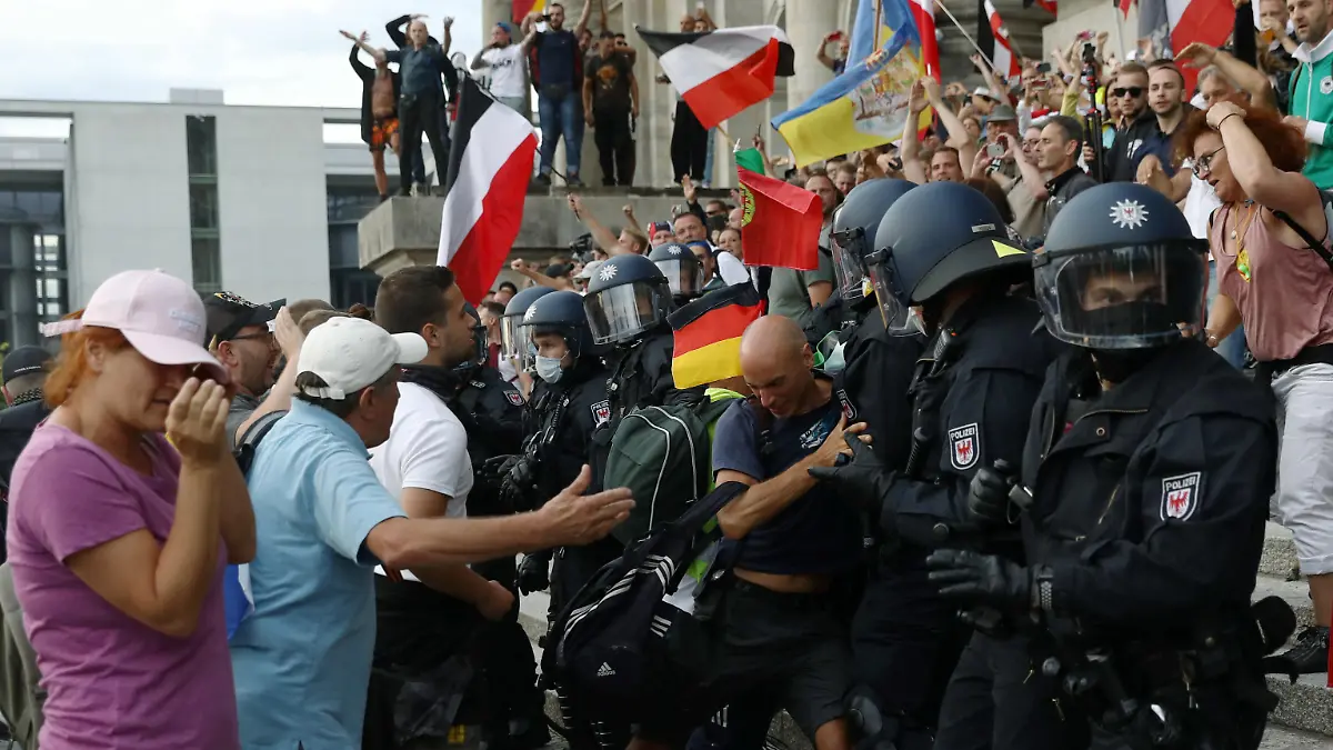Police officers scuffle with a protester in front of the Reichstag Building during a rally against the government's restrictions following the coronavirus disease (COVID-19) outbreak, in Berlin, Germany, August 29, 2020. REUTERS/Christian Mang