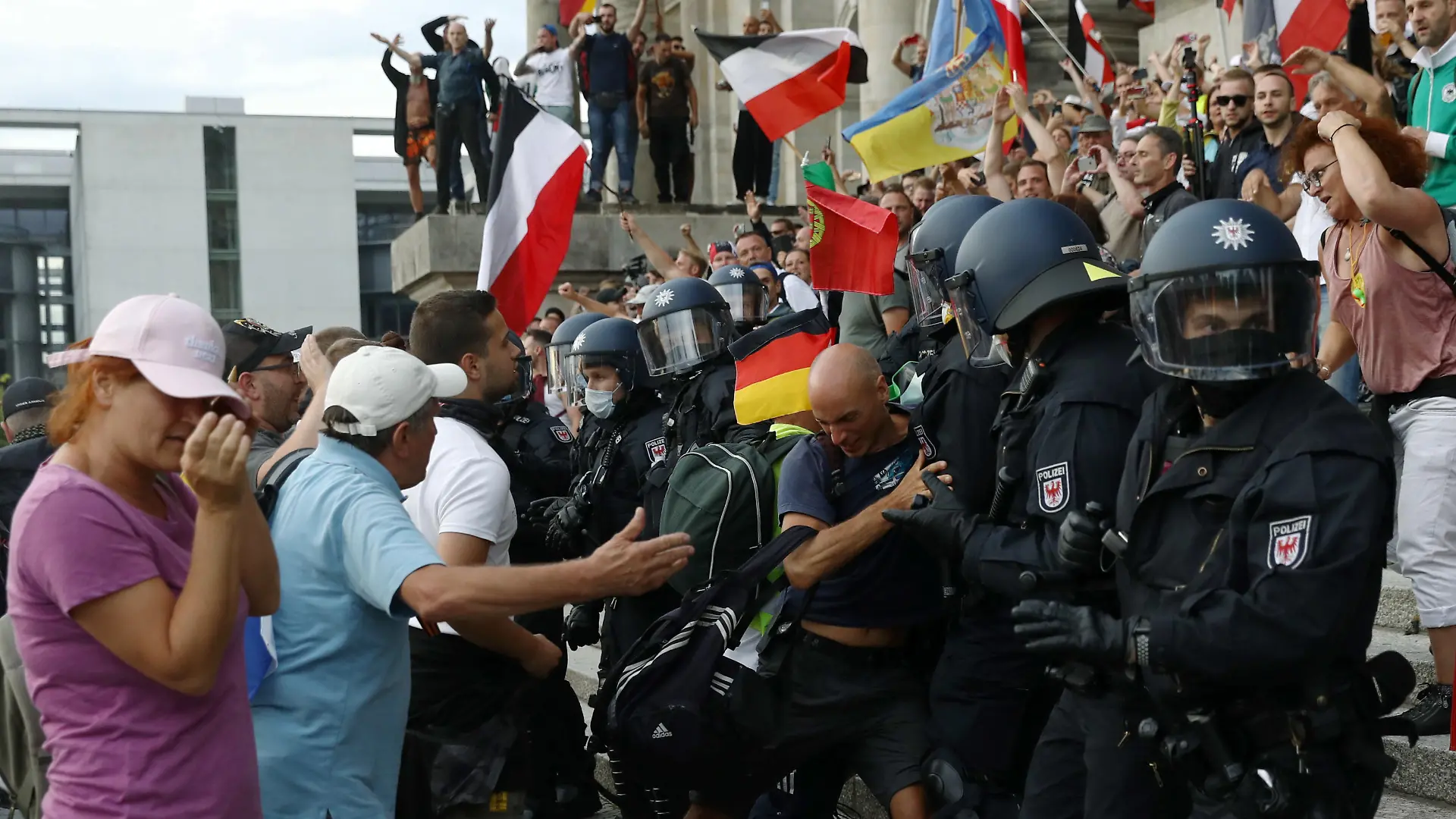 Police officers scuffle with a protester in front of the Reichstag Building during a rally against the government's restrictions following the coronavirus disease (COVID-19) outbreak, in Berlin, Germany, August 29, 2020. REUTERS/Christian Mang
