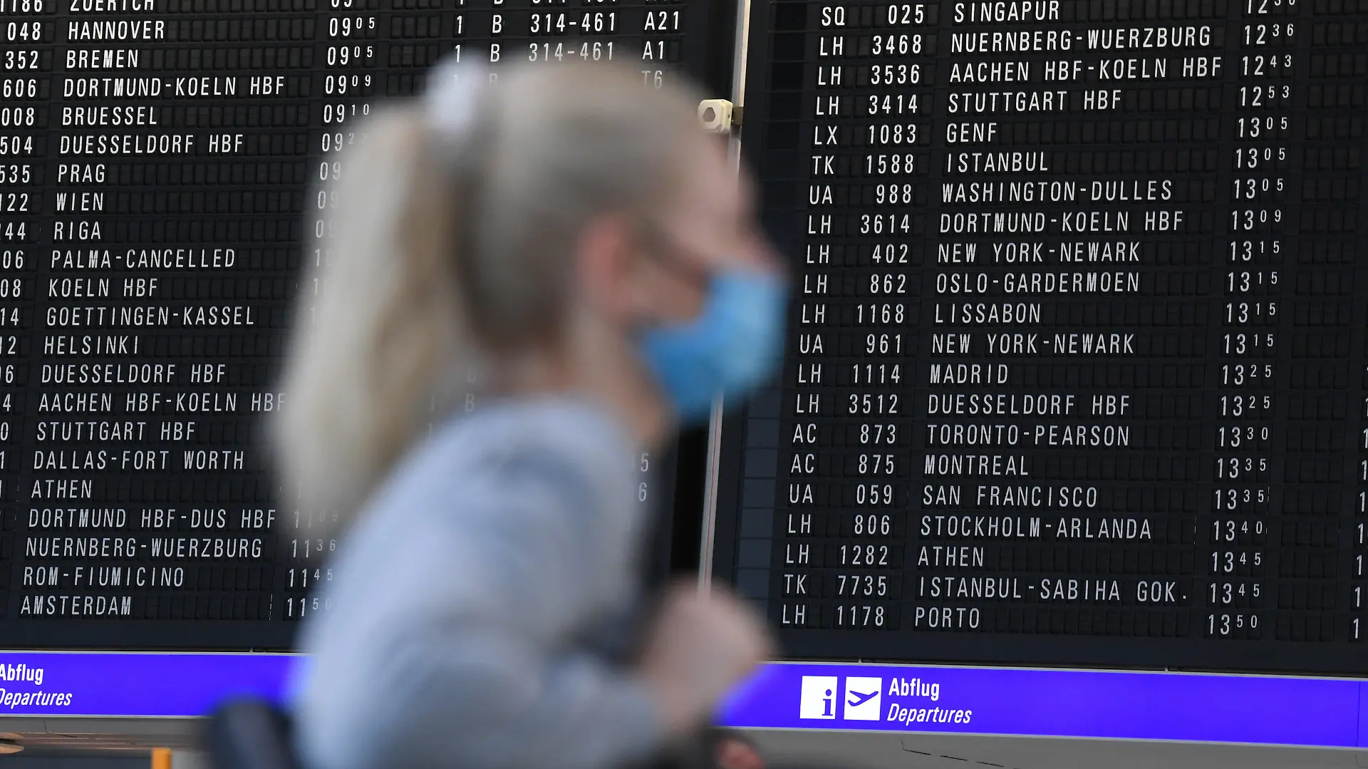 ARCHIV - 15.06.2020, International, Frankfurt/Main: Eine Frau, die einen Mundschutz trägt, steht im Terminal 1 des Frankfurter Flughafens in der Abflughalle vor einer großen Anzeigetafel. Die Bundesregierung hat die Reisewarnung wegen der Corona-Pandemie für mehr als 160 Länder außerhalb der Europäischen Union um zwei Wochen bis zum 14. September 2020 verlängert. Foto: Arne Dedert/dpa +++ dpa-Bildfunk +++